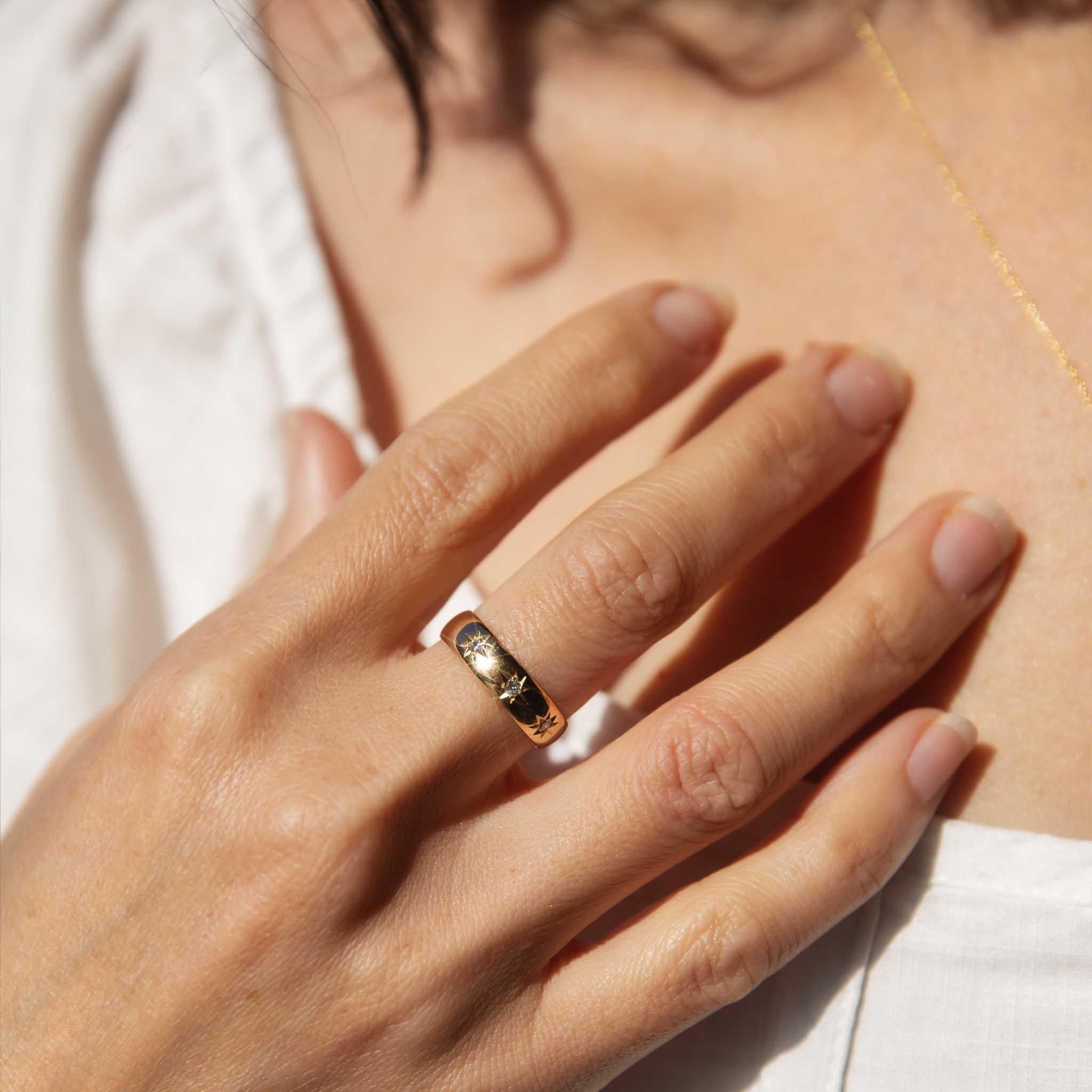 A celestial dance of light, this antique 18 carat gold ring from the late 1890s features three shimmering diamonds set amidst starbursts, evoking the romanticism and elegance of a bygone era. A timeless treasure to be cherished for