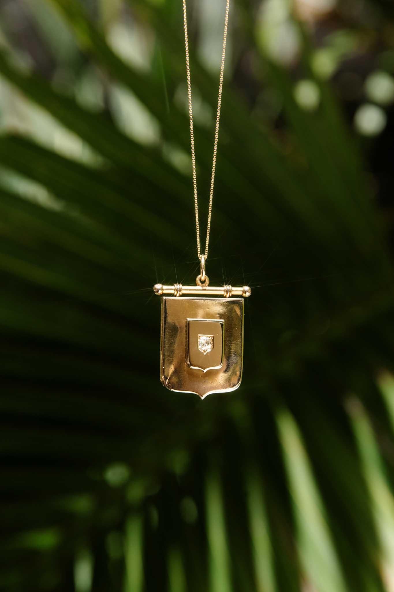 A treasure from a bygone era, the Marshall 1895 Diamond Shield Award Locket in 9 carat gold holds secrets and stories. A sparkling diamond is nestled within a shield motif, set against a polished backdrop. This locket is more than just jewellery; it