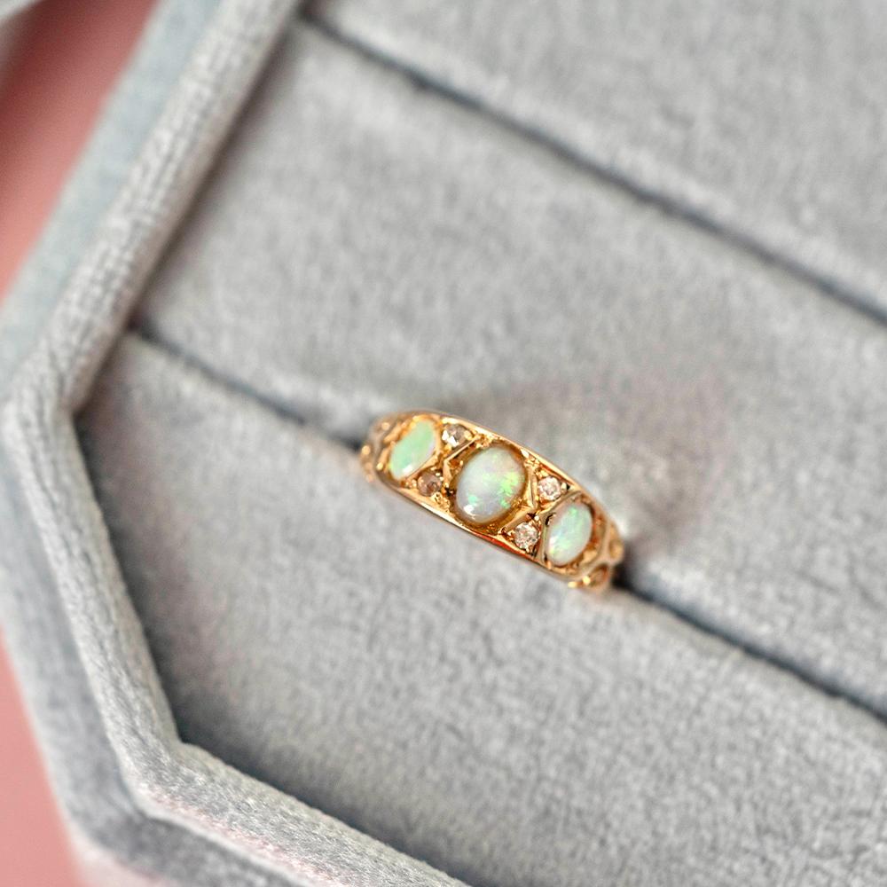 Immerse yourself in the enchantment of the Victorian era with our Antique 1899 Opal Diamond 18ct Gold Ring, a piece that exudes both elegance and historical charm. Centered in this exquisite ring is a captivating opal, known for its mesmerizing play