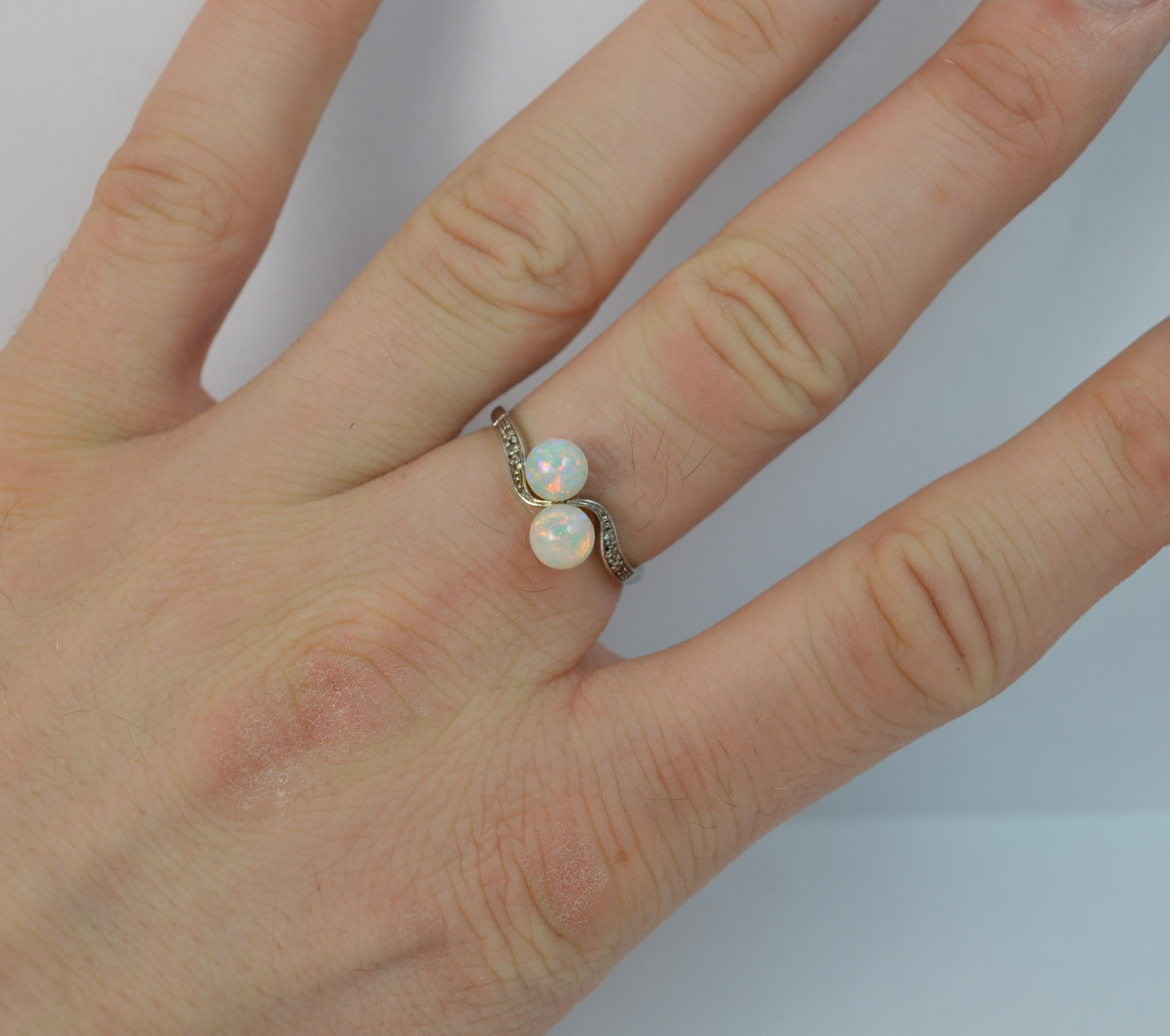 An Edwardian period toi et moi twist ring.
SIZE ; N 1/2 UK, 7 US
Solid 18 carat white gold shank with a platinum head claw setting.

Designed with two opal balls on a twist with three diamonds into the band to each side.

Each opal approx 5.2mm in