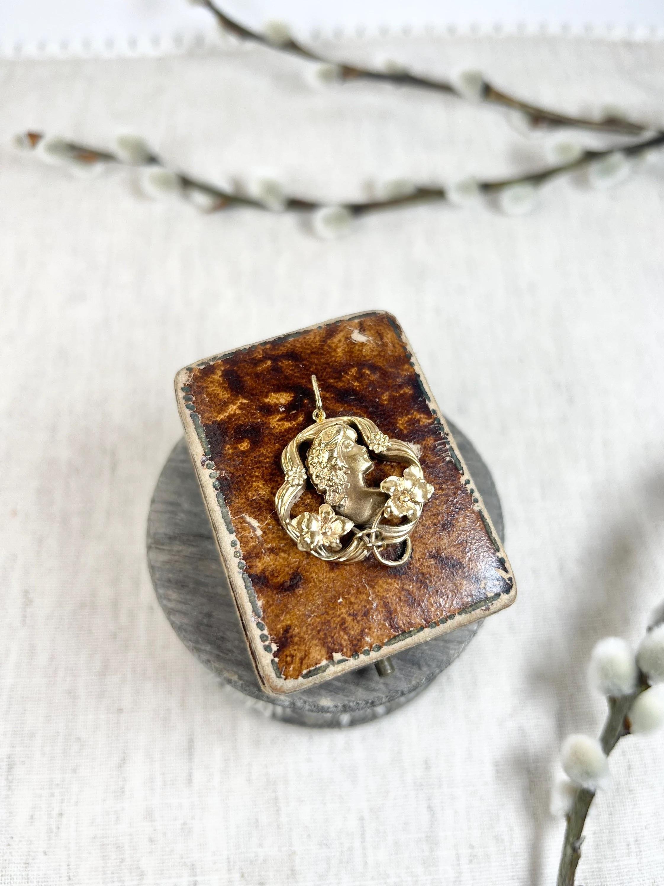 Ciondolo a forma di donna antica 

oro 18ct 

Circa anni '20

Grazioso ciondolo con ritratto di donna in stile Art Nouveau. 
È incorniciata in oro 18 carati con bellissimi dettagli floreali. 

Il ciondolo misura circa 29 mm di altezza e 24,5 mm di