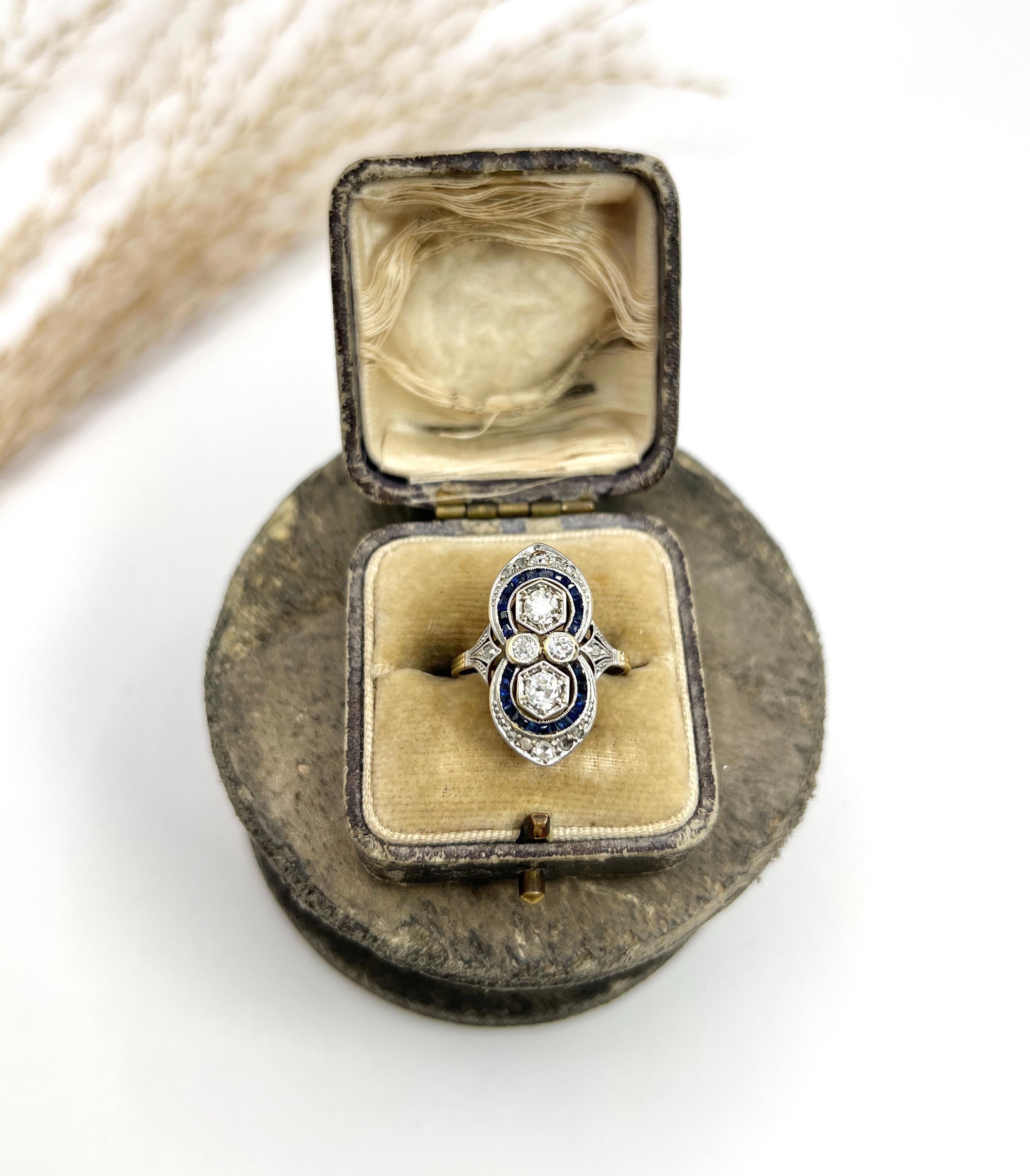 Antique Art Deco Ring

18ct Gold

Circa 1920s

This exquisite 18ct gold original Art Deco ring showcases a stunning up-finger symmetrical figure of eight design, embodying the elegance and grandeur of the era. At its heart, the ring features natural