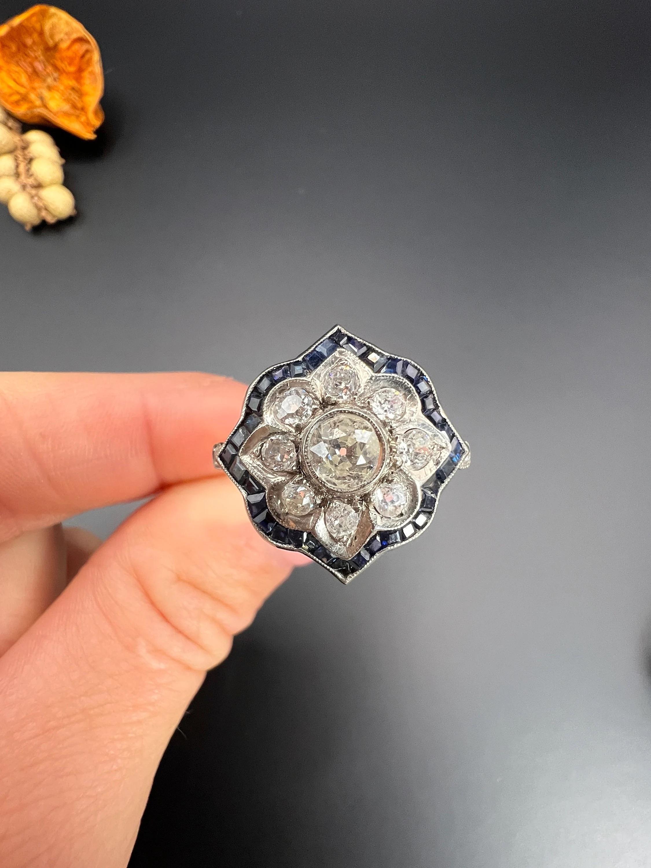 Antique Sapphire Ring 

18ct Gold & Platinum Tested

Circa 1940s

This stunning vintage ring from the 1940s features a fabulous flower design crafted from 18ct yellow gold and platinum. At its centre, a natural diamond takes the spotlight,