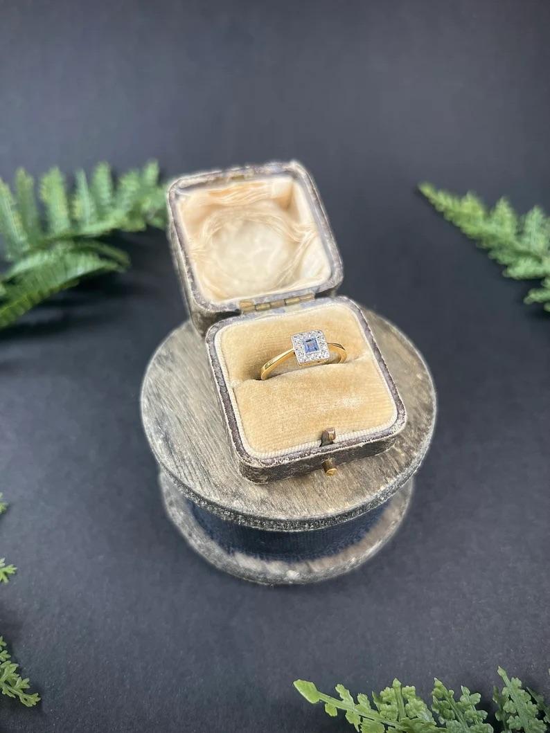 Antique Sapphire Ring 

18ct Gold & Platinum Stamped 

Circa 1900

Makers Mark F H L 

This exquisite Edwardian ring features a stunning, square-cut pale blue sapphire that is elegantly set in a platinum illusion setting. The sapphire's subtle hue