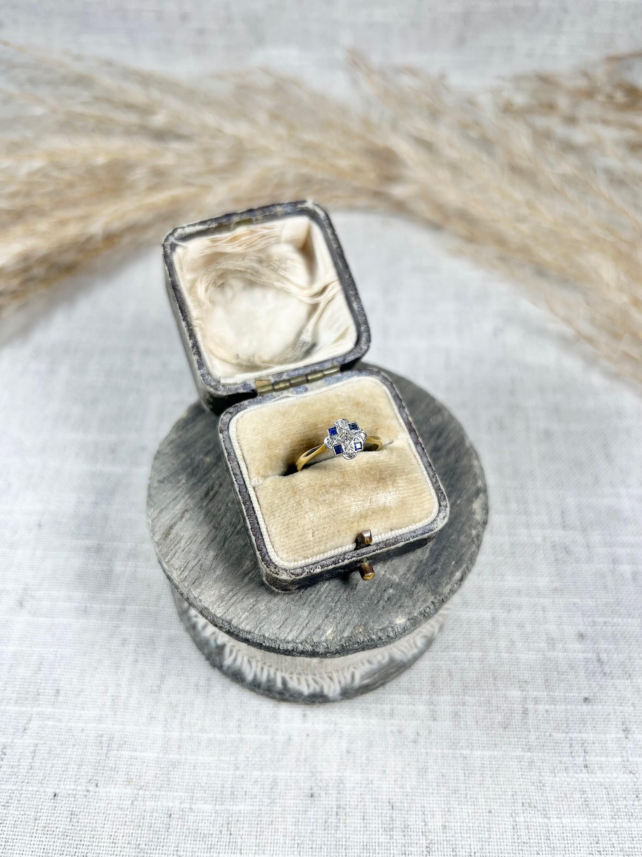 Sapphire Deco Ring 

18ct Gold & Platinum Stamped 

Circa 1910

This stunning Art Deco ring is truly one of a kind. Crafted from 18ct gold and platinum, the ring is stamped to guarantee its authenticity. The clover shape of the ring is adorned with