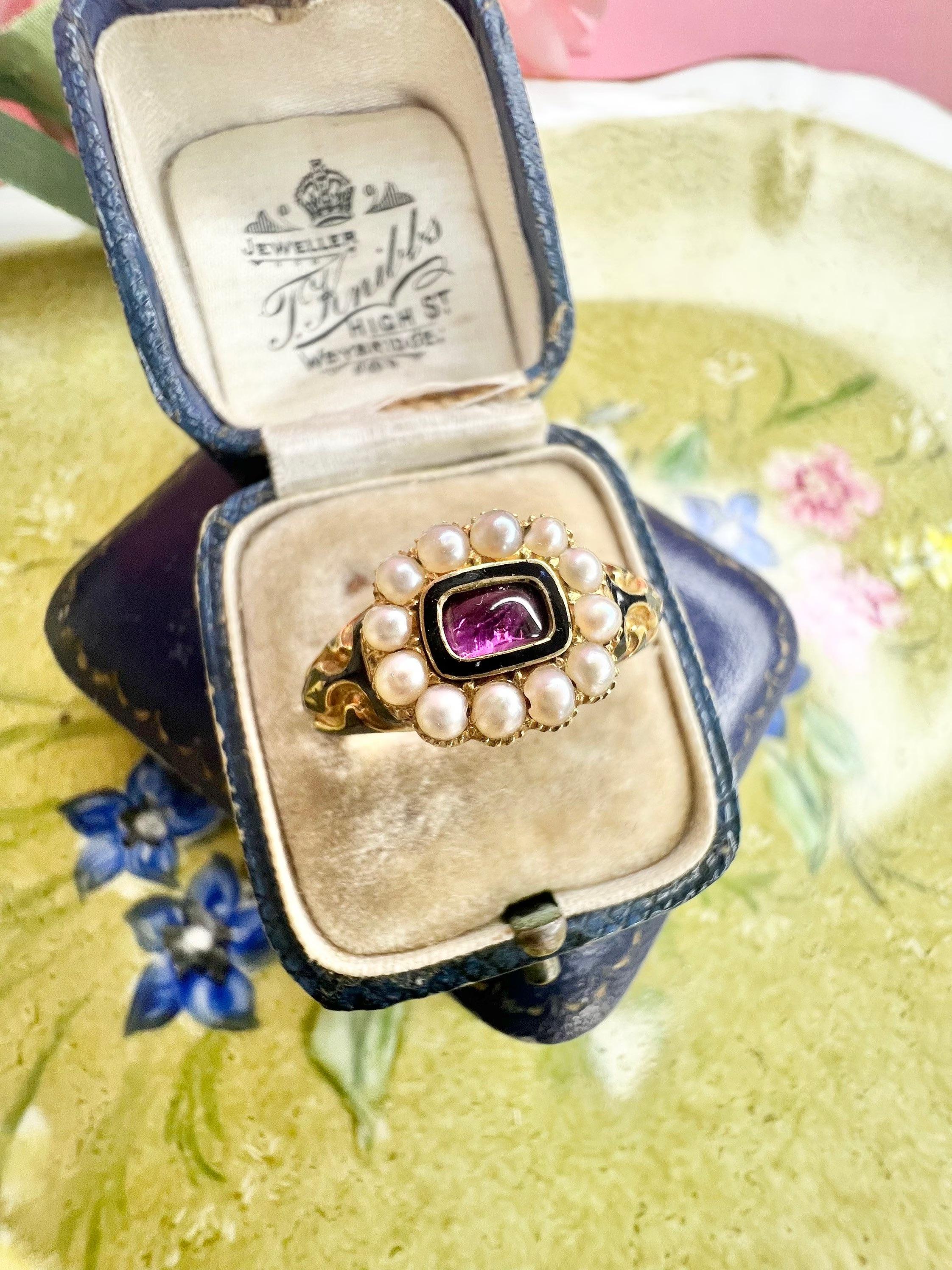 Antique Mourning Ring 

18ct Gold 

Hallmarked London 1844 

Makers Mark S R 

Beautiful Victorian Mourning Ring. Set with Natural Seed Pearls & a Cabochon Foil Backed Gemstone- Possibly a Garnet Stone. 
Beautifully Decorated Shoulders with Black