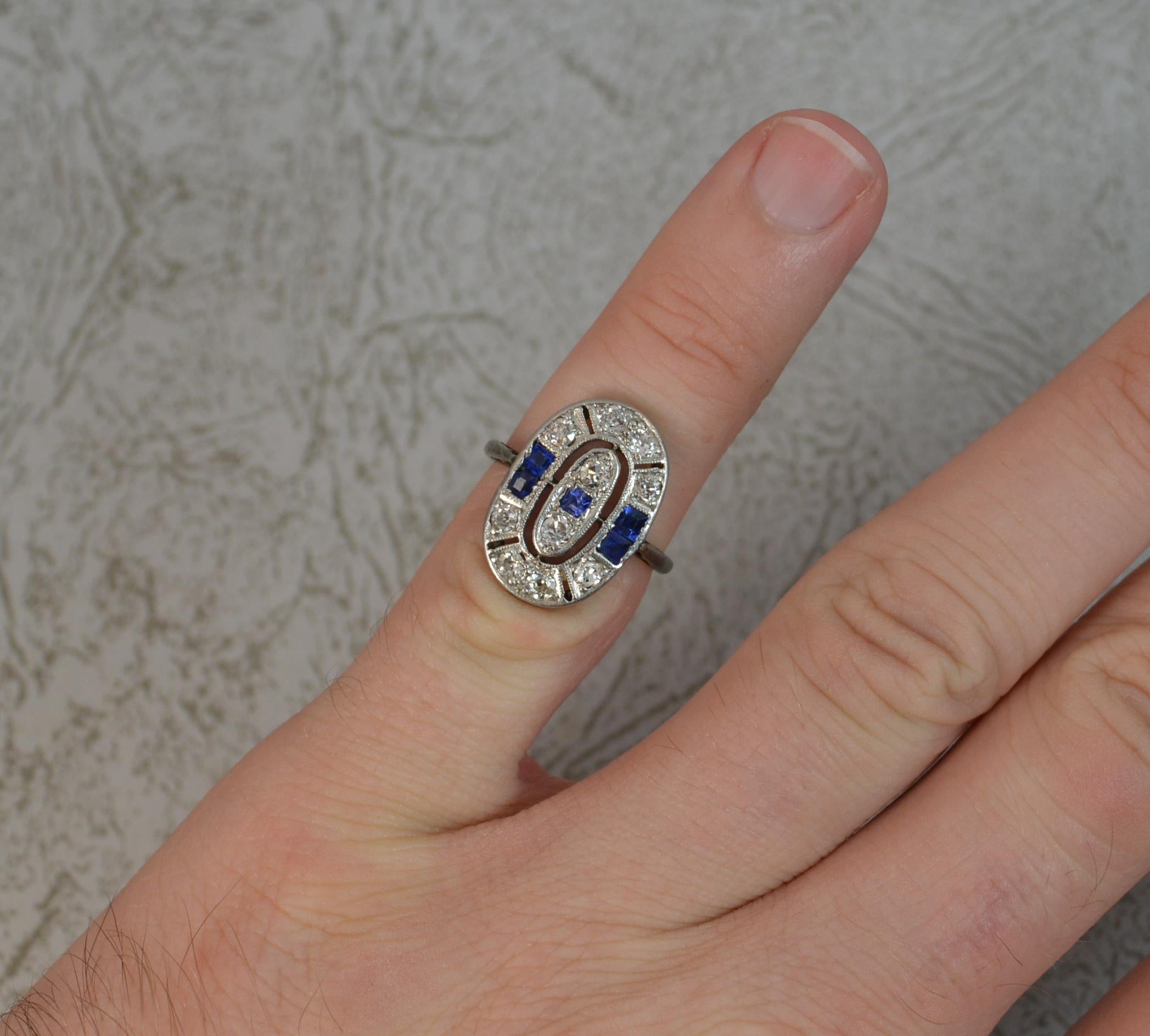 A superb 18ct gold, sapphire and diamond panel ring.
18 carat white gold shank with platinum head setting.
12mm x 17mm cluster head.
Formed with five princess cut blue sapphires and ten round cut diamonds.

CONDITION ; Very good for age. Clean and