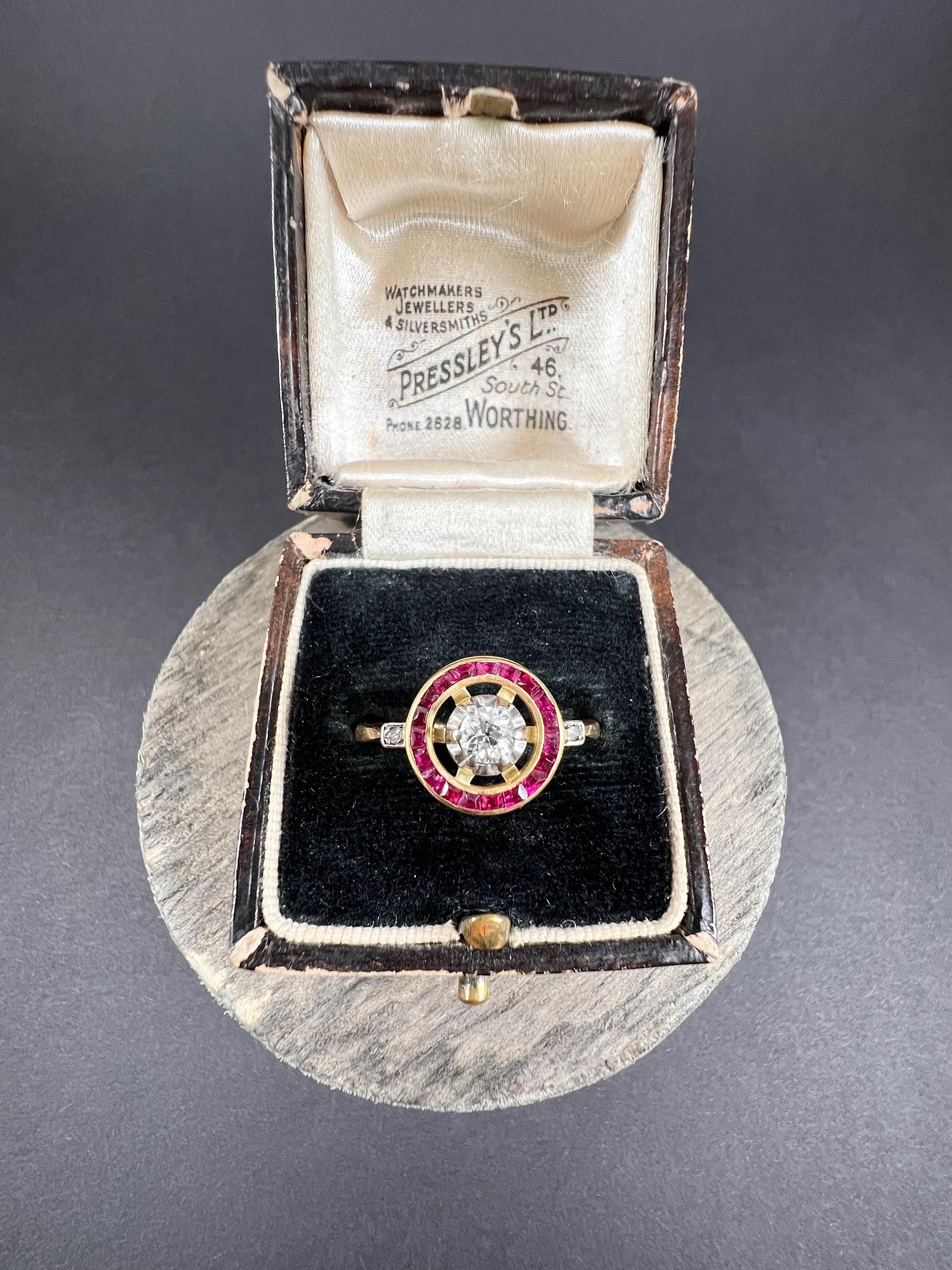 Antique Target Ring 

18ct Yellow Gold Tested

Circa 1910

Introducing an exquisite 18ct yellow gold Edwardian era target ring, featuring a stunning centre natural diamond encircled by a halo of captivating natural rubies. This timeless piece, circa