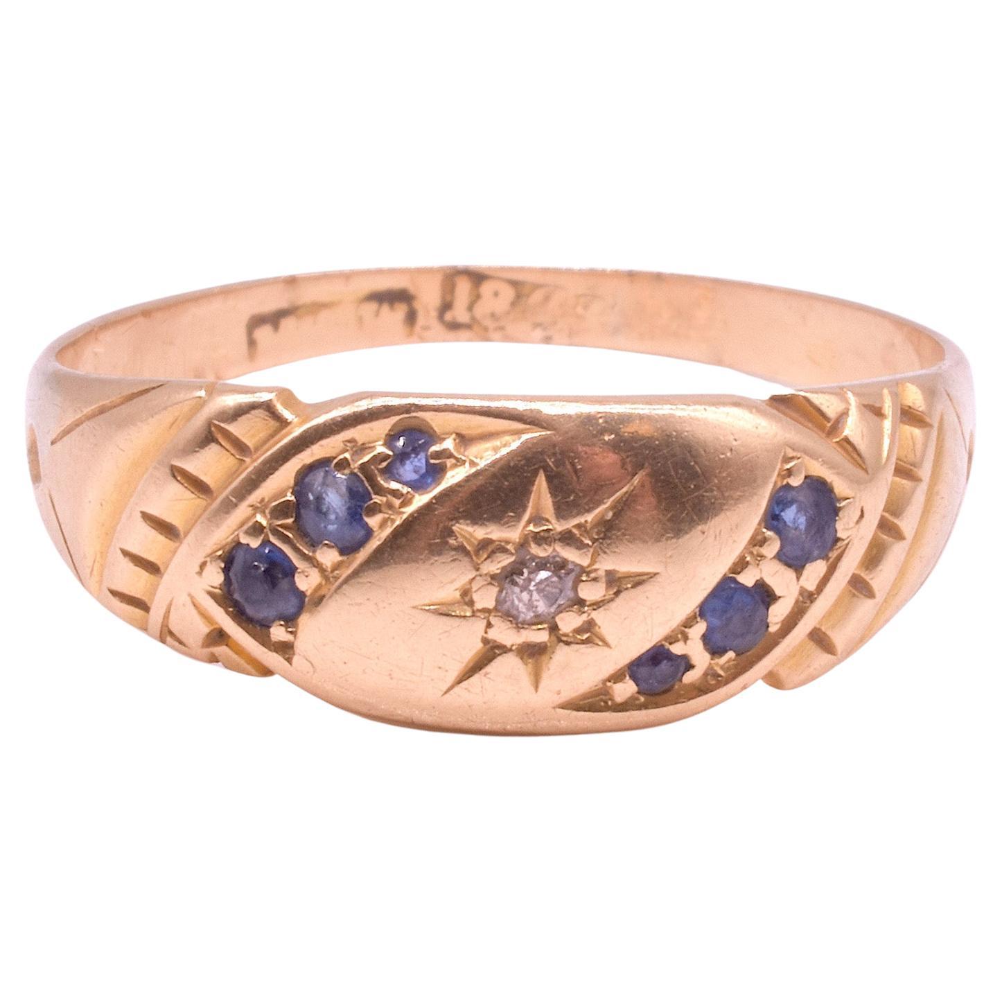 This charming old European cut diamond and sapphire gypsy set ring from around the turn of the century is an unusual combination of 3 sapphire stones set in a banner flanking a central star set diamond. The buttery yellow gold sets off the colors of