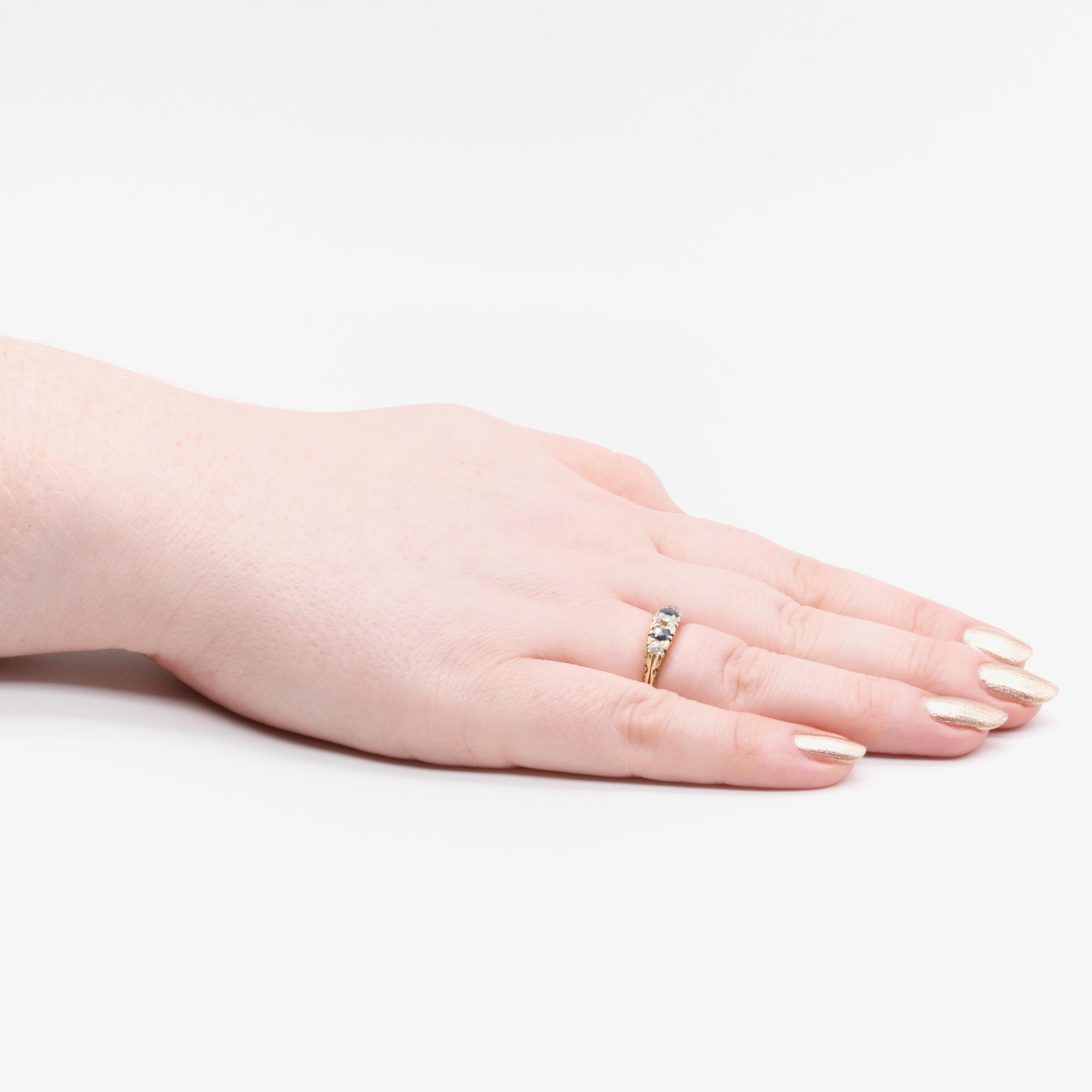 An antique diamond, sapphire, and yellow gold ring, comprising one larger and two smaller old mine cut diamonds and two oval cut blue sapphires, set in 18 karat yellow gold, to a band of 18 karat yellow gold. 

The ring is set to the centre with a