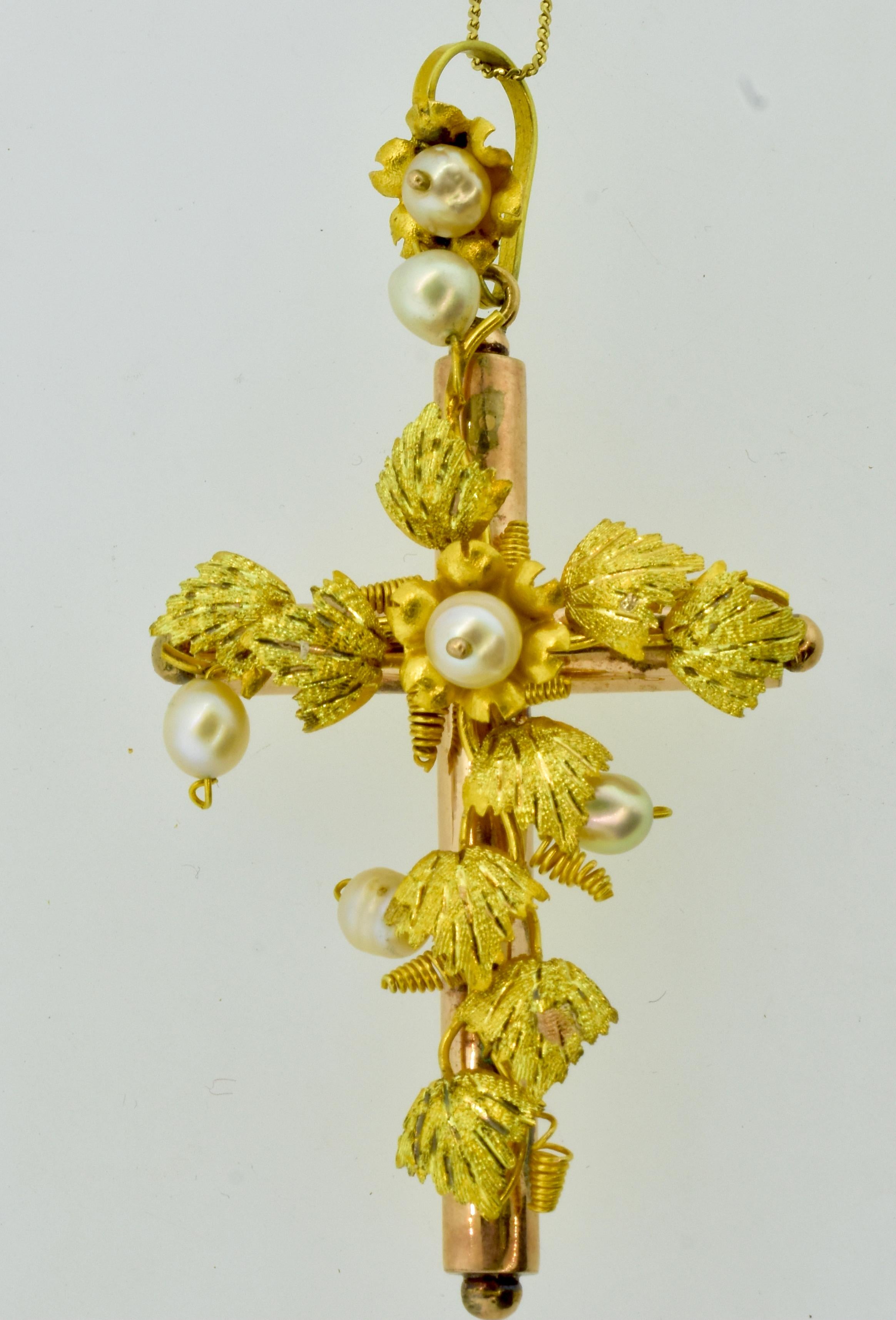 Antique cross in pink and yellow 18K gold and  5 natural fresh water pearls are set in the center and top of the cross, in the bale and set along the leaves in an asymmetrical design.  The carved leaves are in yellow gold and well done.  The cross