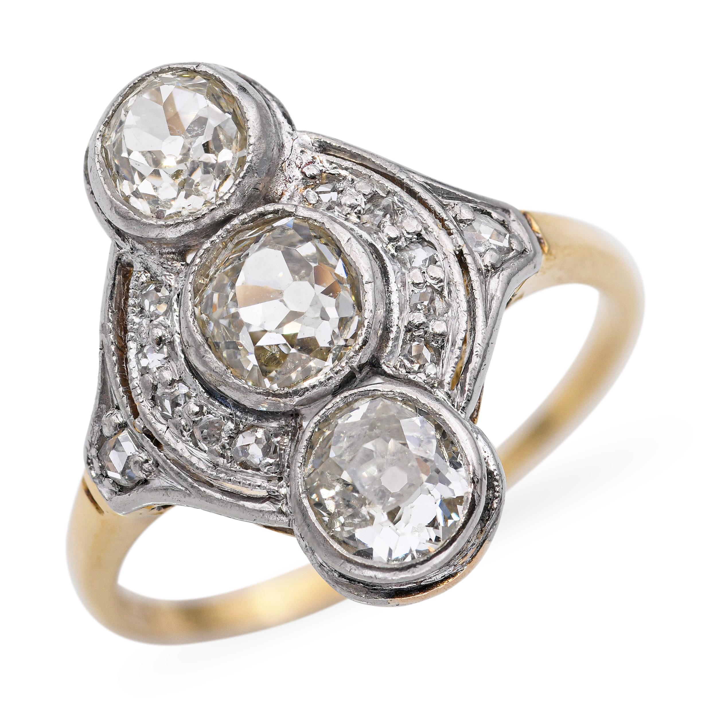 Questo raffinato anello da cena vintage è realizzato in una combinazione di oro giallo 18 carati e platino e sfoggia un intramontabile design con tre pietre e diamanti. Il trio di diamanti scintillanti simboleggia il passato, il presente e il