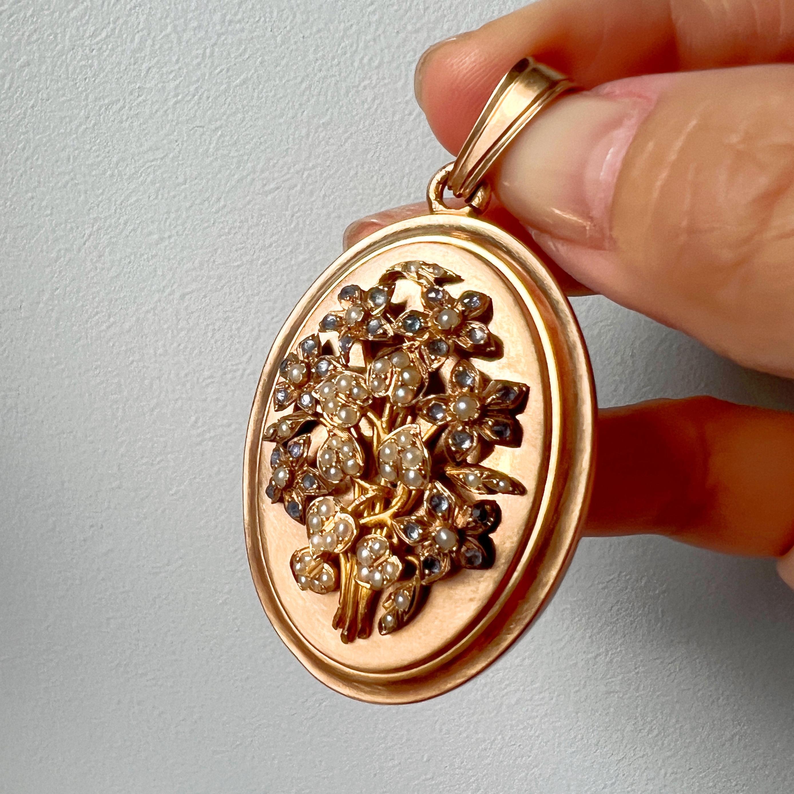 For sale a beautiful 18K gold, Victorian-era locket pendant, which features a lovely bouquet of flowers meticulously crafted from natural seed pearls and radiant blue sapphires on its front cover. The petals and leaves are expertly shaped, providing