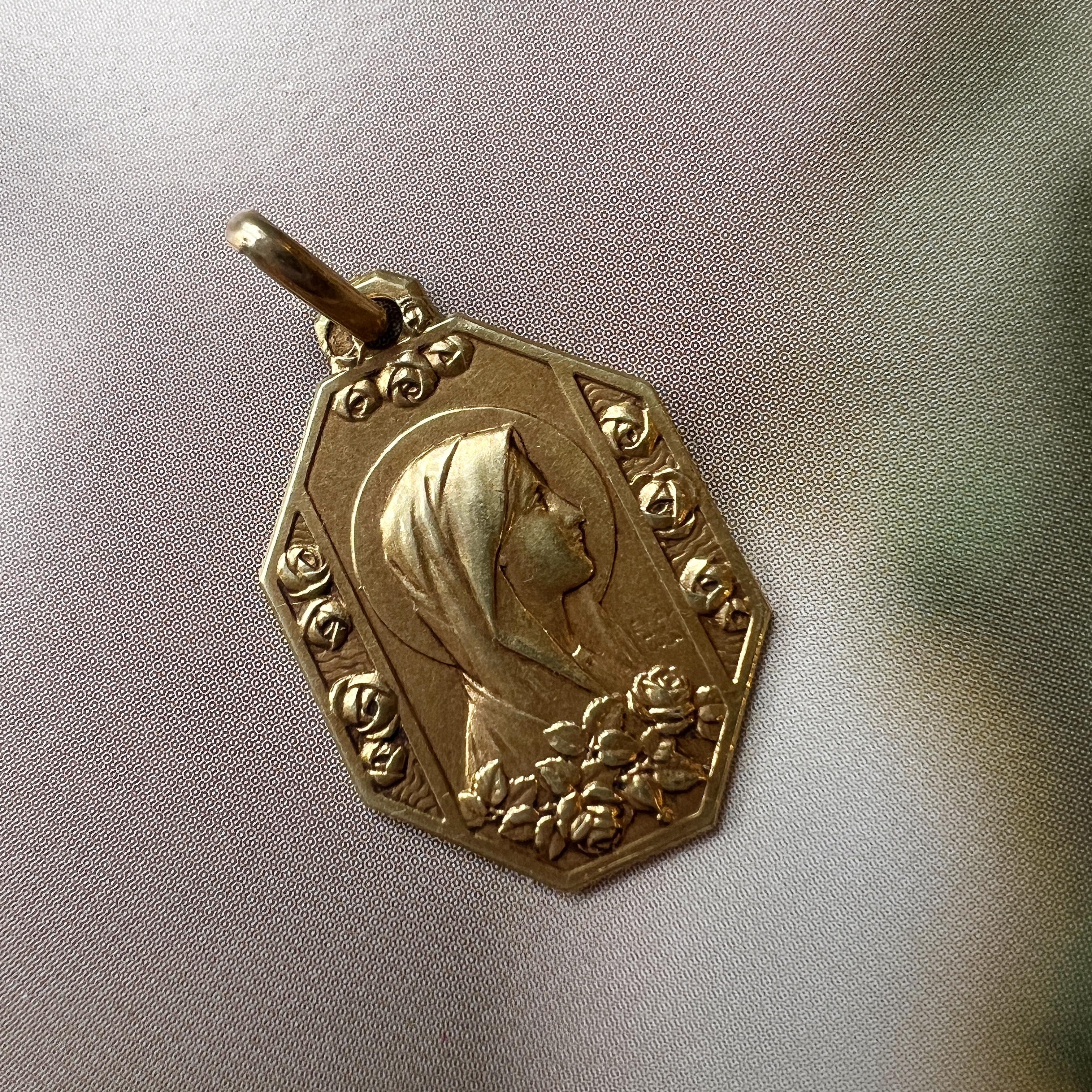 For sale a very beautiful French antique 18K medal pendant featuring the Virgin Mary on one side decorated with the delicate rose flowers. And on the other side, a praying scene refers to the appearance of the Virgin at Lourdes. The beautiful face