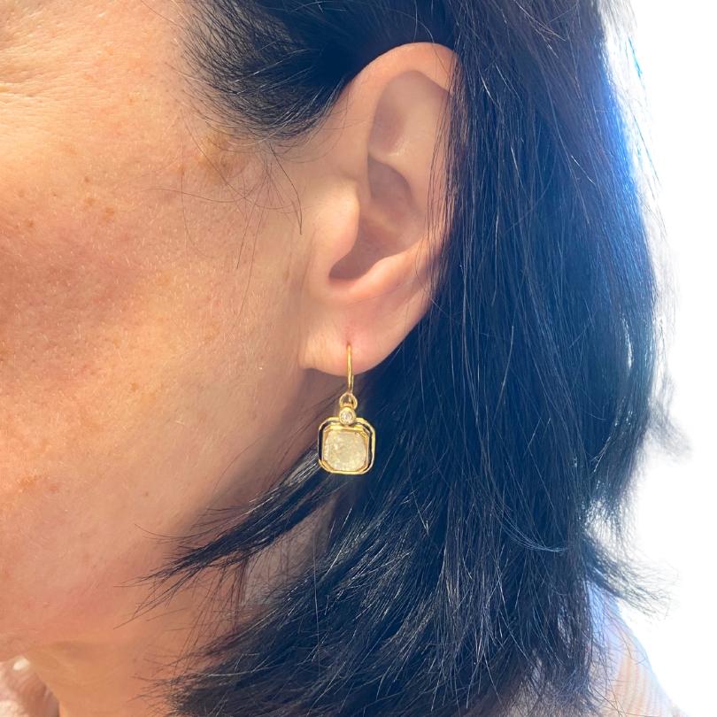 These beautiful antique earrings are crafted in 18k gold and feature a design that can be appreciated from both the front and back. The front showcases a diamond at the center, framed in gold with a fine border of dark enamel. Above each main stone