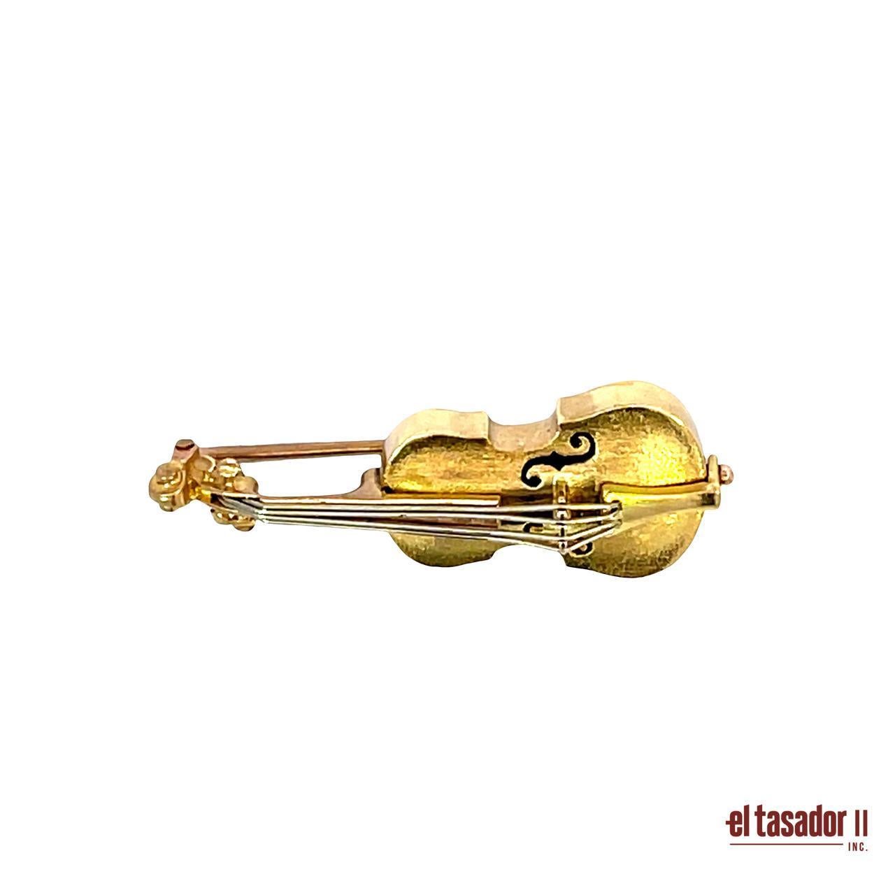 Questa squisita spilla antica è realizzata magistralmente in oro 18 carati e pesa 6,8 grammi. Disegnato a forma di chitarra, presenta dettagli delicati che evidenziano l'eleganza e la maestria dei gioielli di un'epoca passata. Le calde tonalità