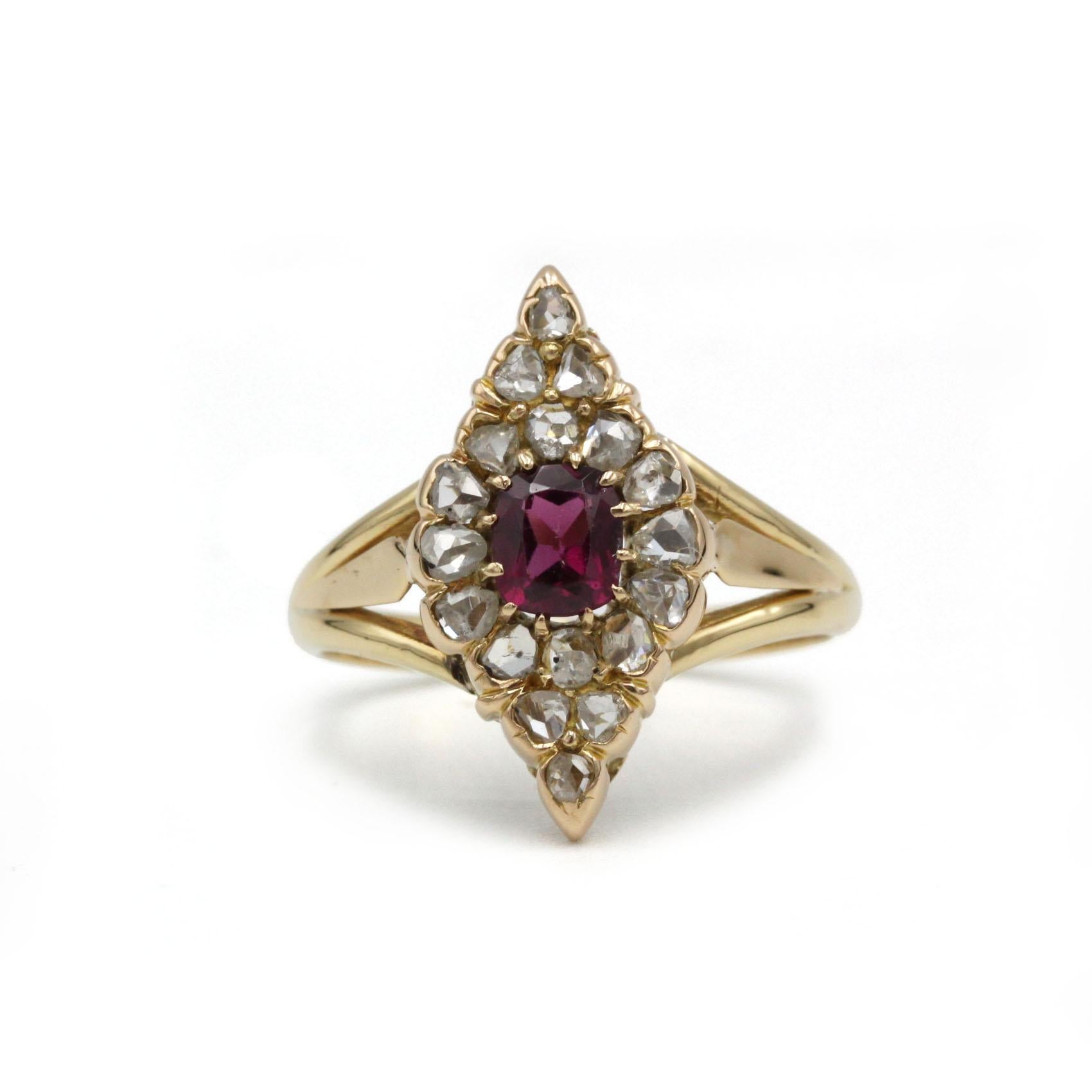 This antique marquise ring is crafted in 18K yellow gold and set with a vivid natural ruby at its center, framed by a halo of rose-cut diamonds. The elongated marquise silhouette gives the piece an elegant presence on the hand, while the rose-cut