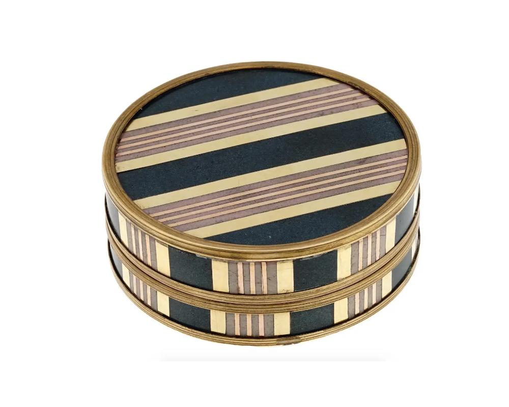 An antique 18k gold mounted circular box with various plates of inlaid stones. The inside of the box is fully lined with tortoiseshell like material. The removable cover presents a decoration of stone inlaid stripe patterns, as well as the box