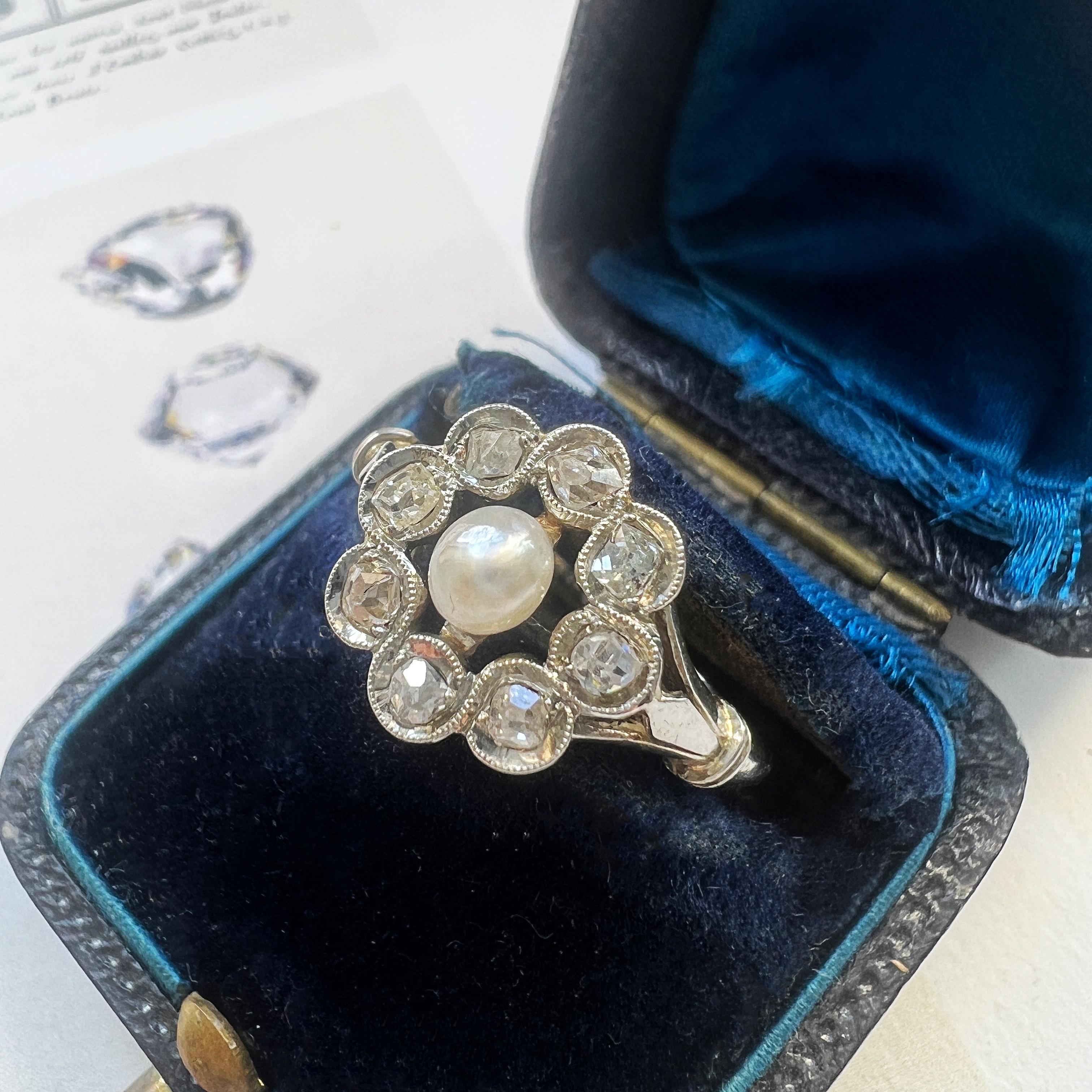 For sale a lovely French work, 18K white gold cluster ring, featuring a white color, natural pearl in the center. The pearl has a semi-rounded shape which makes it different from the standardized human cultured pearls we have today. It shows a very
