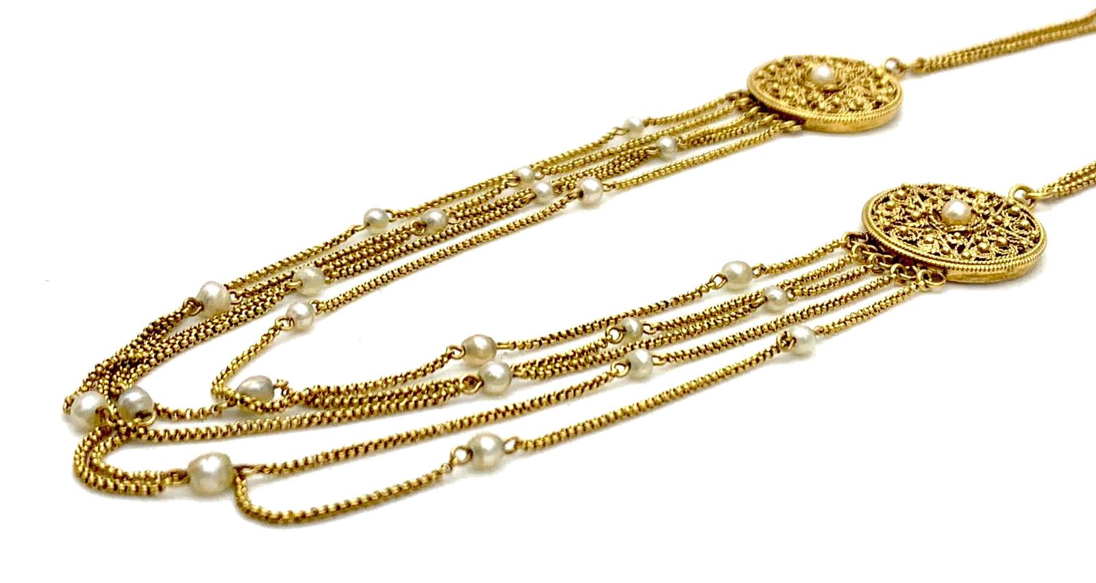 This unusual necklace was created in 1975 ca. It features two round discs suspended from gold chains attached to a grooved barrel clasp. Each disk is decorated with twisted gold wire ornaments, gold balls  and a star with five points. In the centre