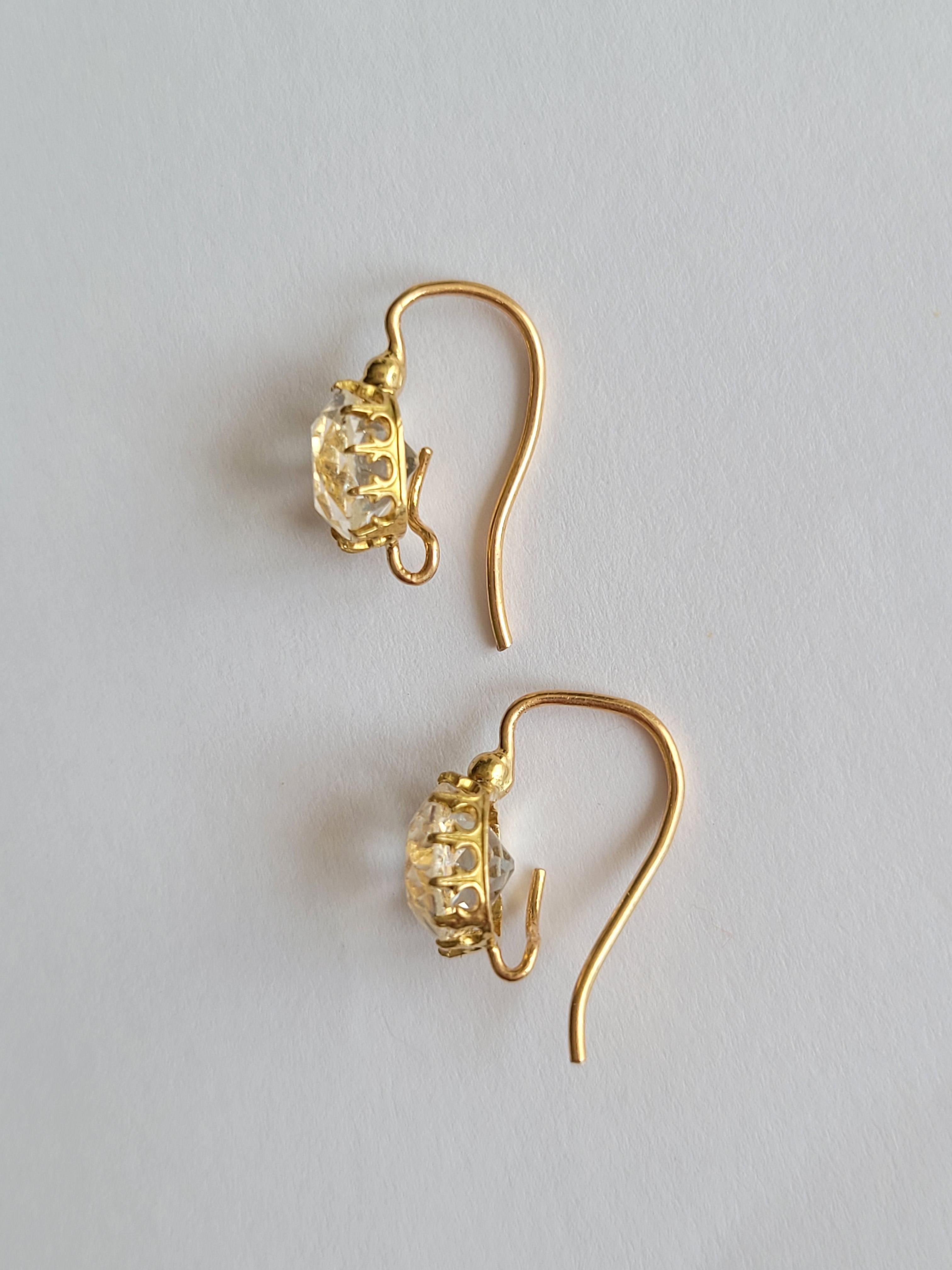These exquisite late 19th-century earrings showcase a timeless elegance, crafted from lustrous 18-carat gold and adorned with mesmerizing rock crystal stones in a regal crown-style setting. The petite yet impactful design boasts a total drop of 13mm