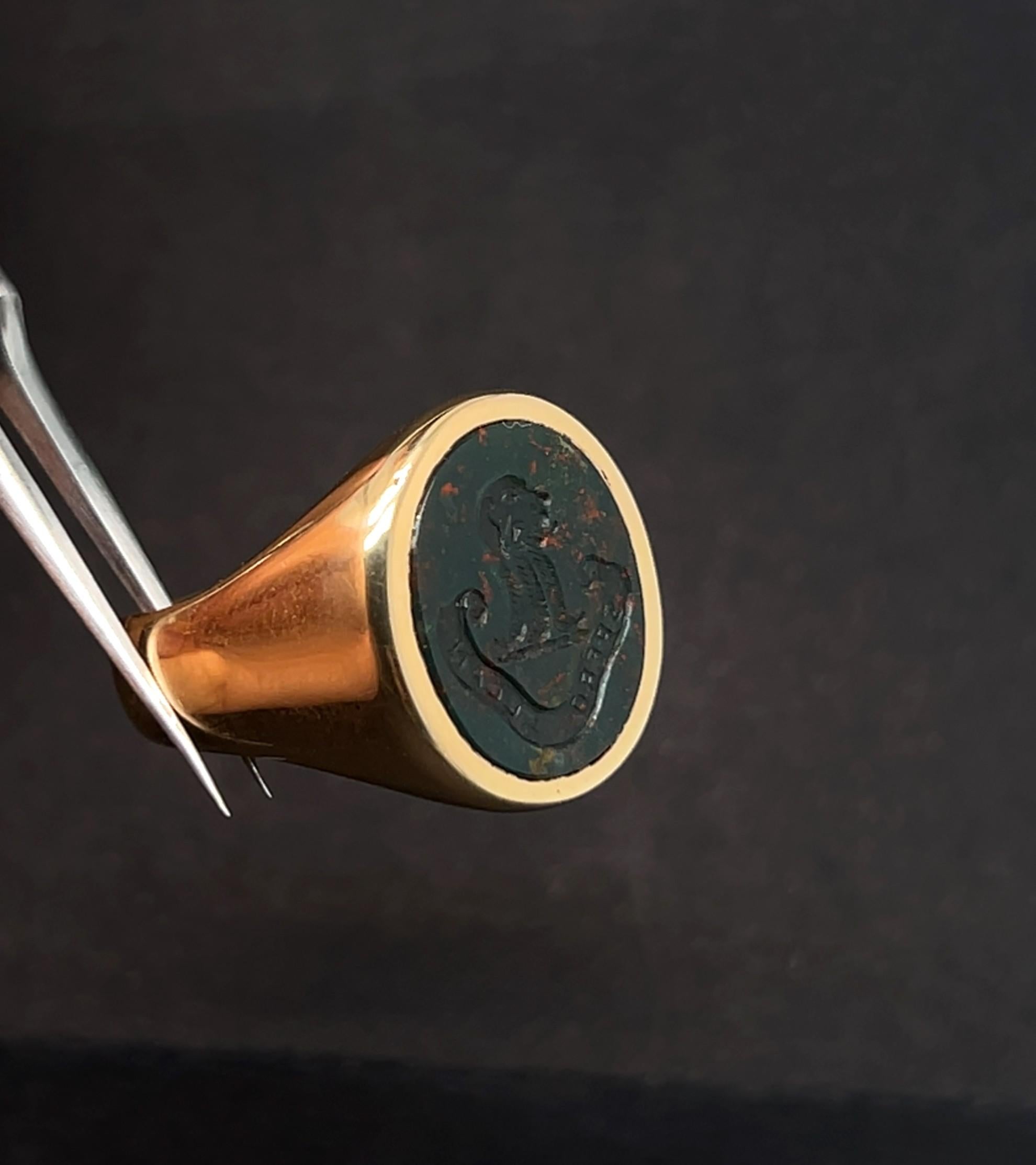 Cette chevalière ancienne et distinguée allie l'élégance intemporelle de l'or jaune 18 carats massif aux tons riches et profonds d'une pierre de sang (héliotrope) gravée à la main. L'intaille finement sculptée, représentant des armoiries ou un