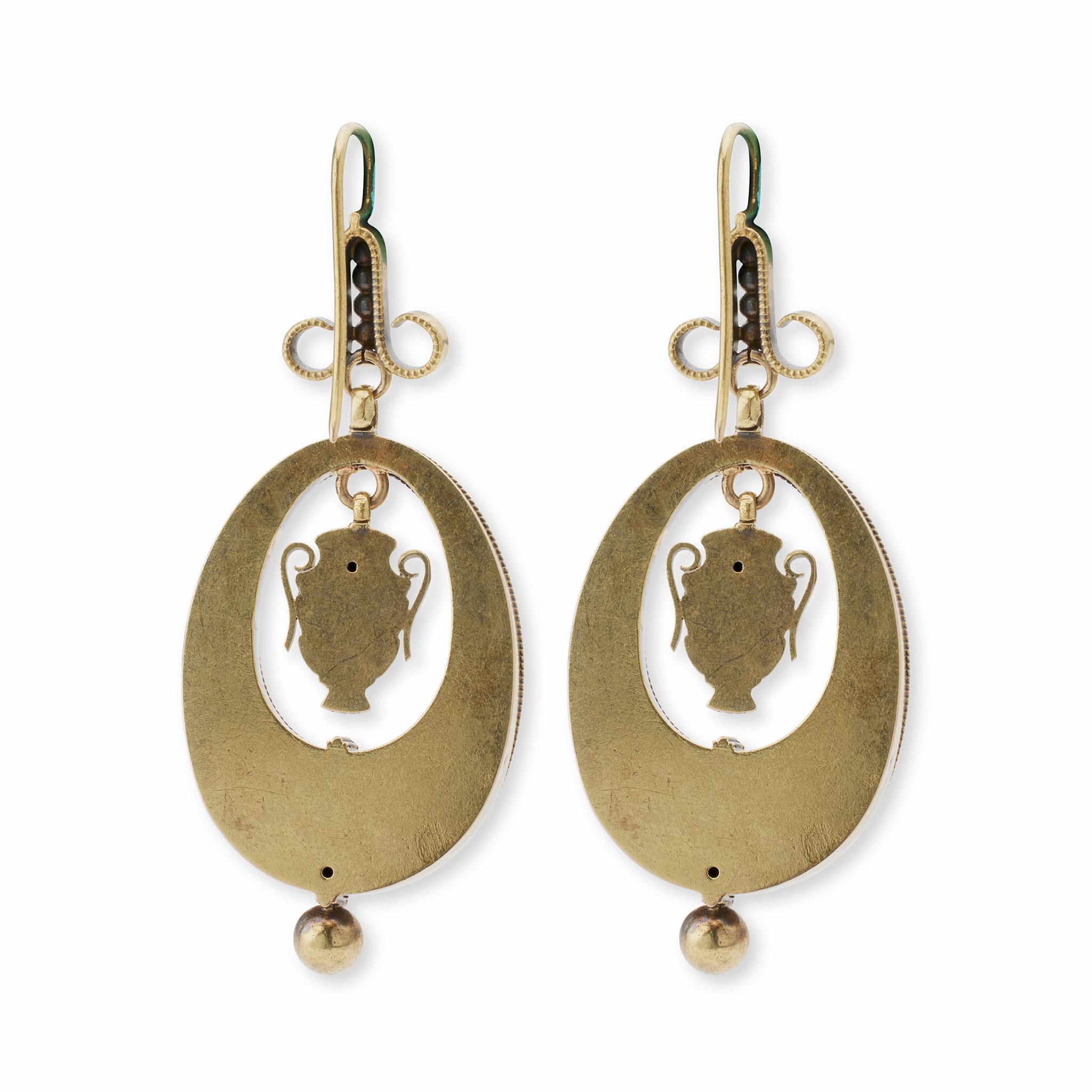 Dating from the 1870s, these pendant earrings are composed of 18K gold. Each is designed as a line of spheres flanked by scrolls suspending an elongated open drop with wirework laurel wreath motifs and large pendant bead, framing a flexibly