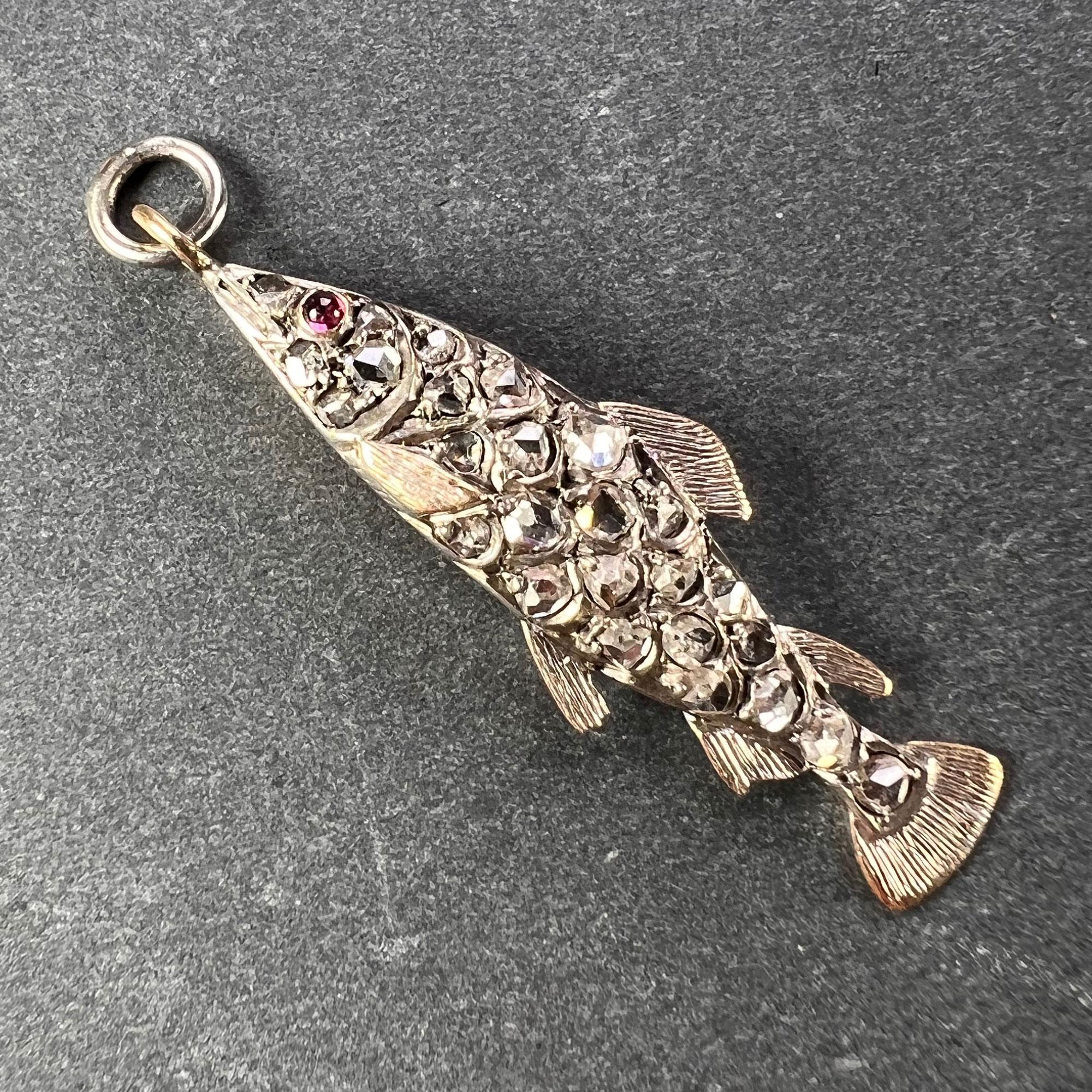 Pendentif de charme ancien en forme de poisson en or et argent serti de 26 diamants taillés en rose d'un poids total estimé à 0,65 carats et d'un œil en rubis cabochon. Non marqué mais testé comme or rose 18 carats (18K).

Dimensions : 3,2 x 1 x