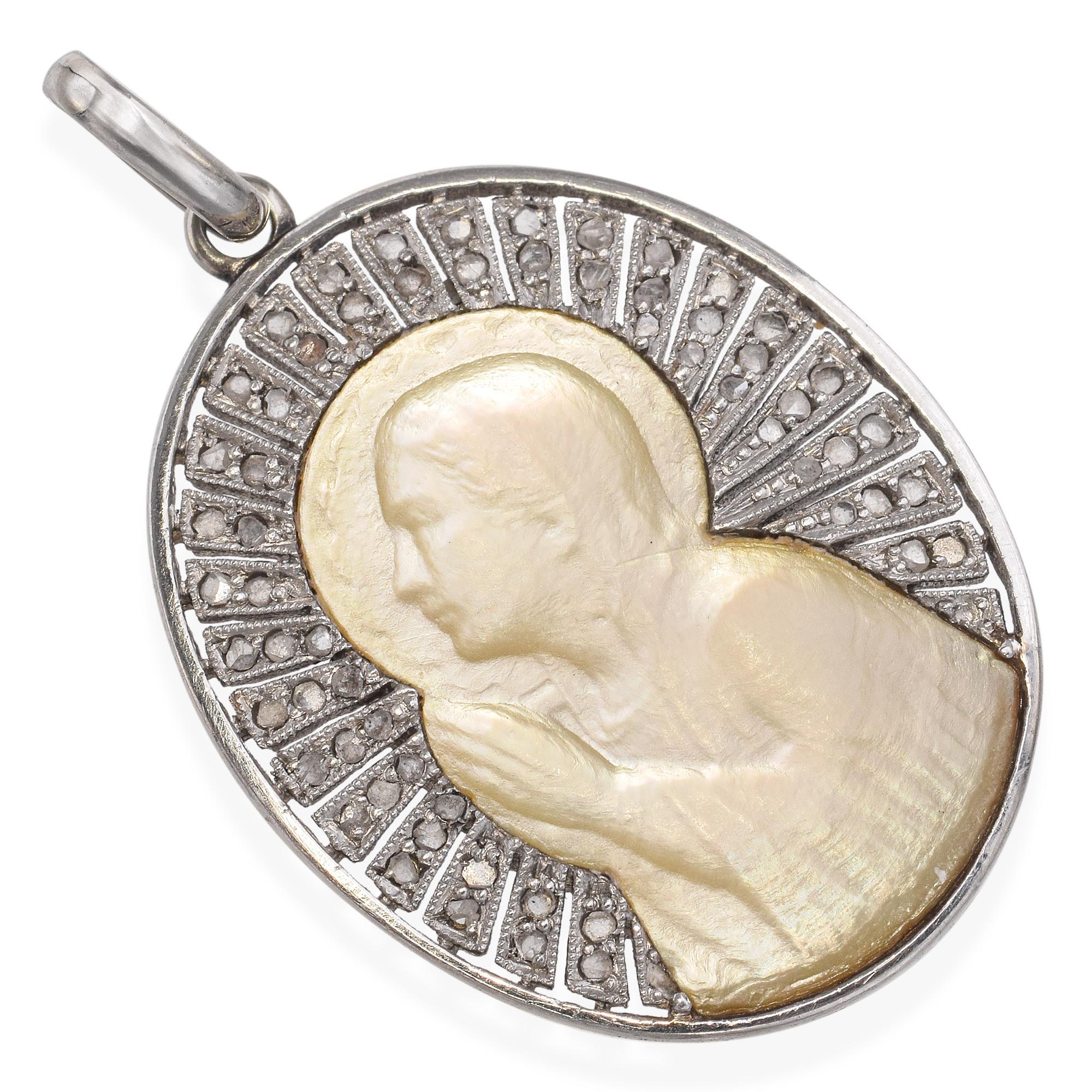 Elegant et intemporel, ce pendentif antique présente un camée en nacre magnifiquement sculpté à la main et serti dans un luxueux or blanc 18 carats. La surface lumineuse et irisée de la nacre met en valeur les fins détails de la sculpture, tandis