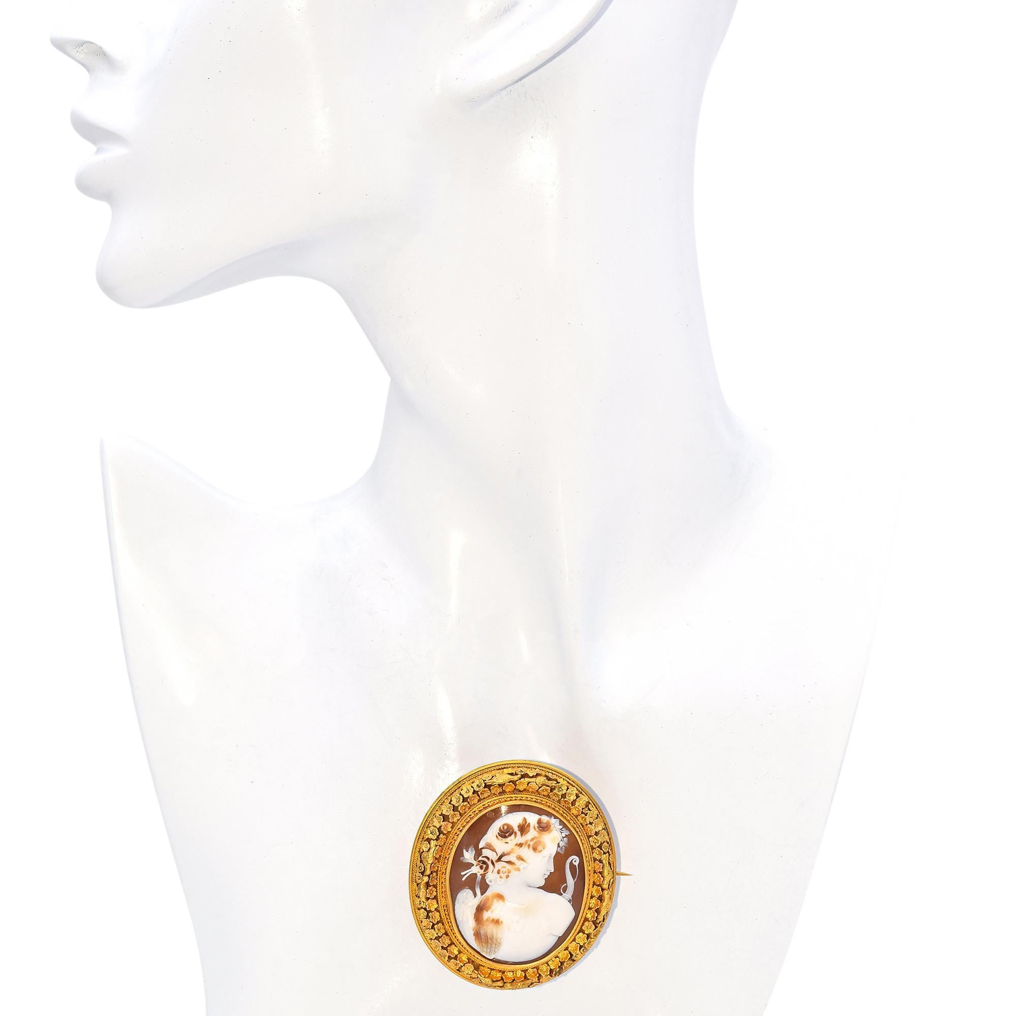 This exquisite brooch features an intricately carved cameo depicting a classical Eros figure with delicate detailing. The cameo is set in a lavish 18k yellow gold frame adorned with ornate floral motifs, enhancing its elegance.

Weight: 20