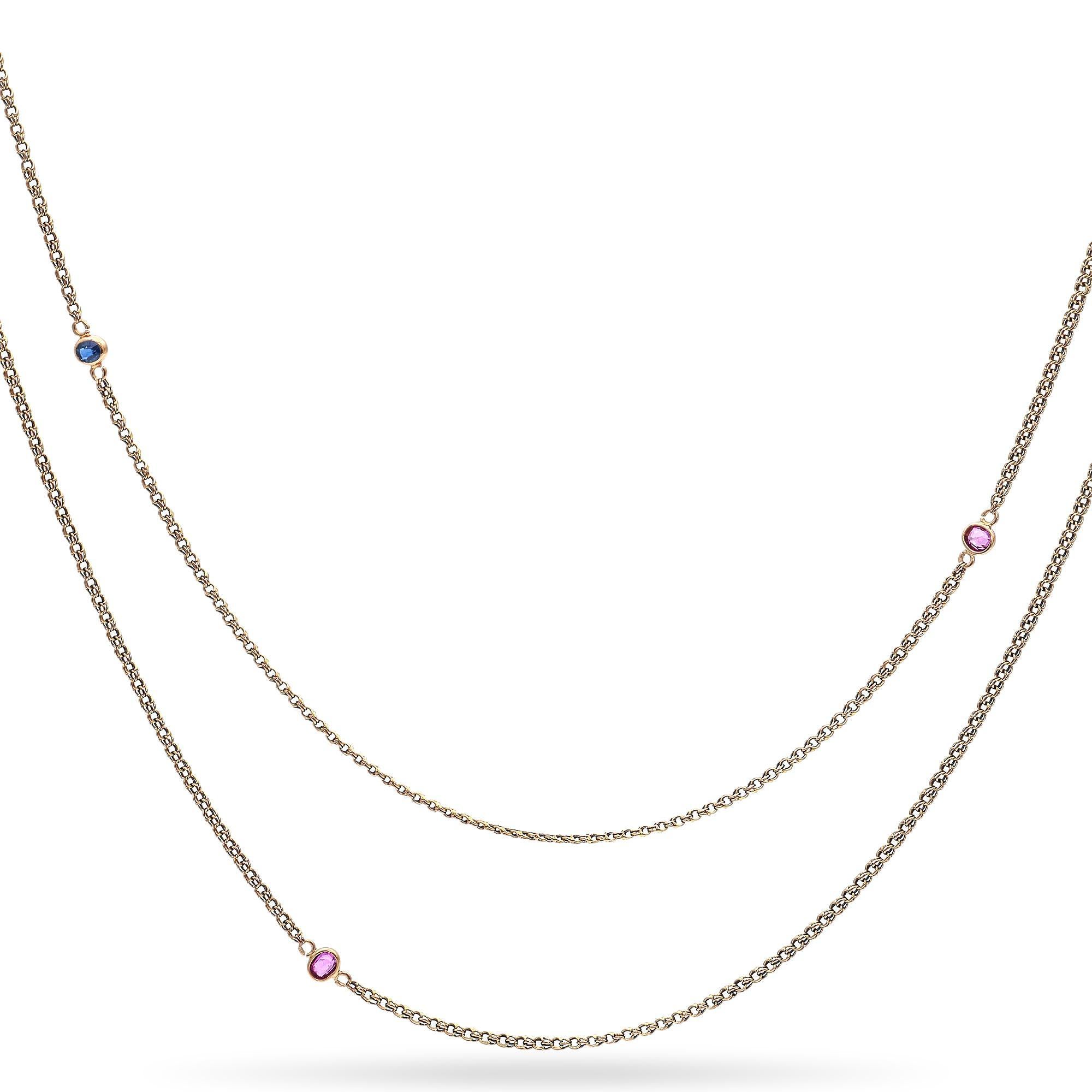 A striking and elegant chain necklace.
This piece features a series of vibrant blue and pink sapphires, each bezel set along the length of the chain.
The chain is crafted from a warm-toned 18k gold, providing a rich contrast to the colorful