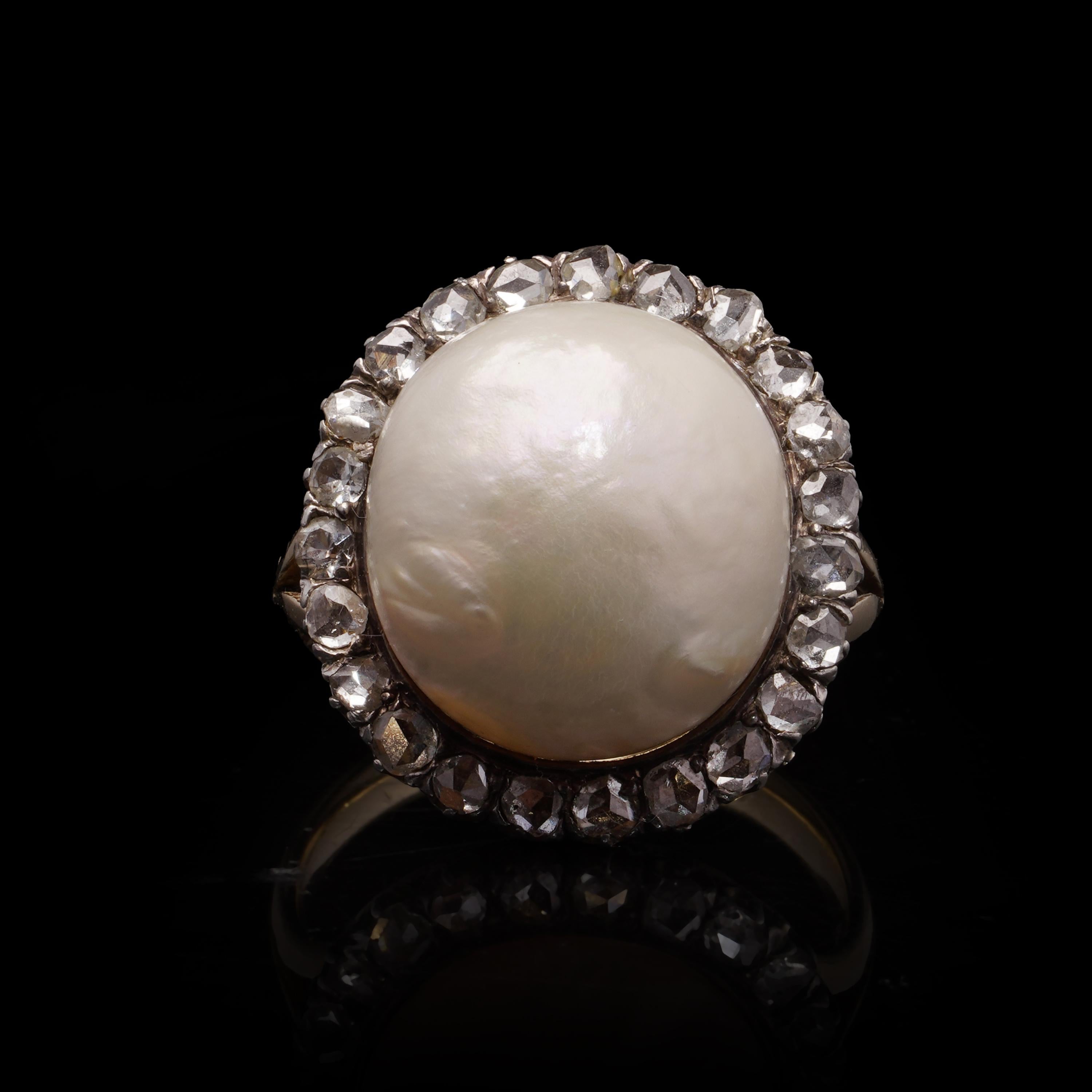 A striking antique cluster ring crafted in a combination of 18kt yellow gold and silver, centering on a large 15 mm pearl framed by 23 rose-cut diamonds. The domed design with the pearl bezel-set in silver-topped gold and surrounded by a halo of