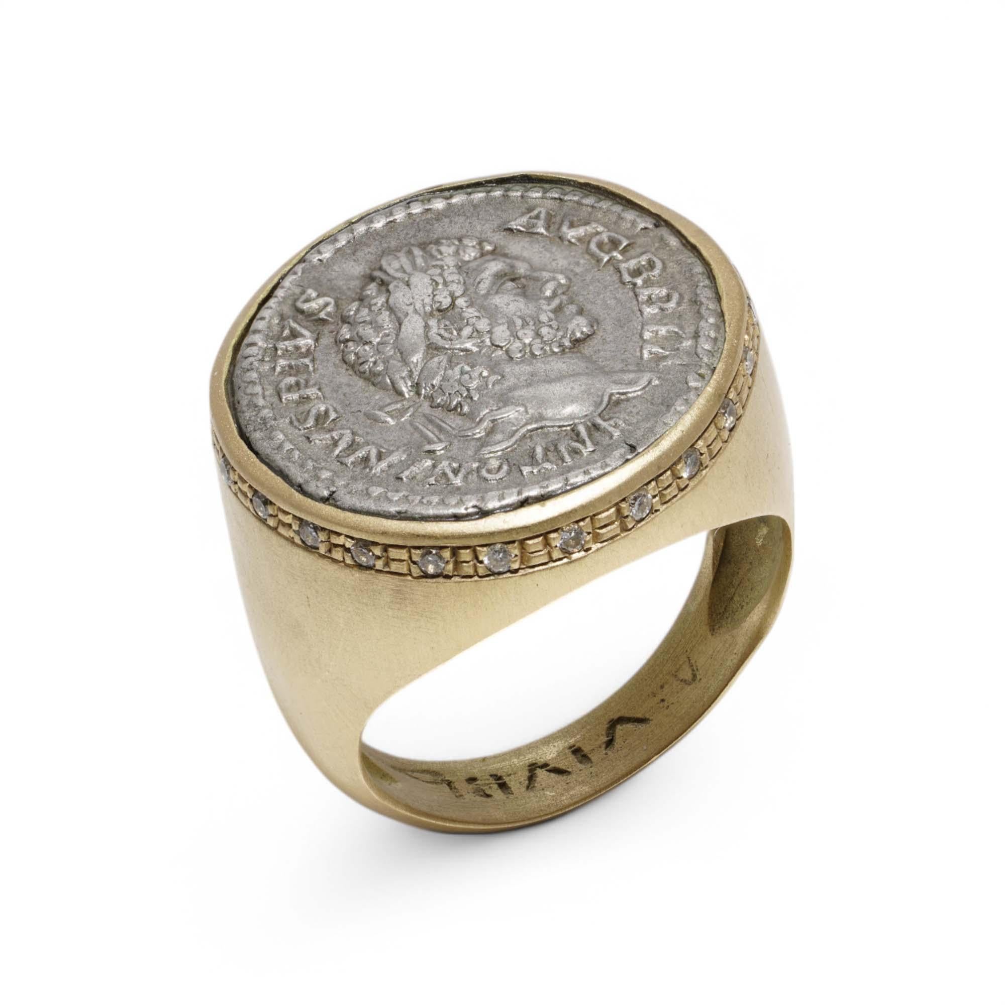 A distinguished 18kt yellow gold signet ring featuring an authentic Ancient Roman silver denarius depicting Emperor Antoninus Pius (reigned AD 138–161). The bezel is intricately set with this historical coin, showing the emperor’s laureate profile,