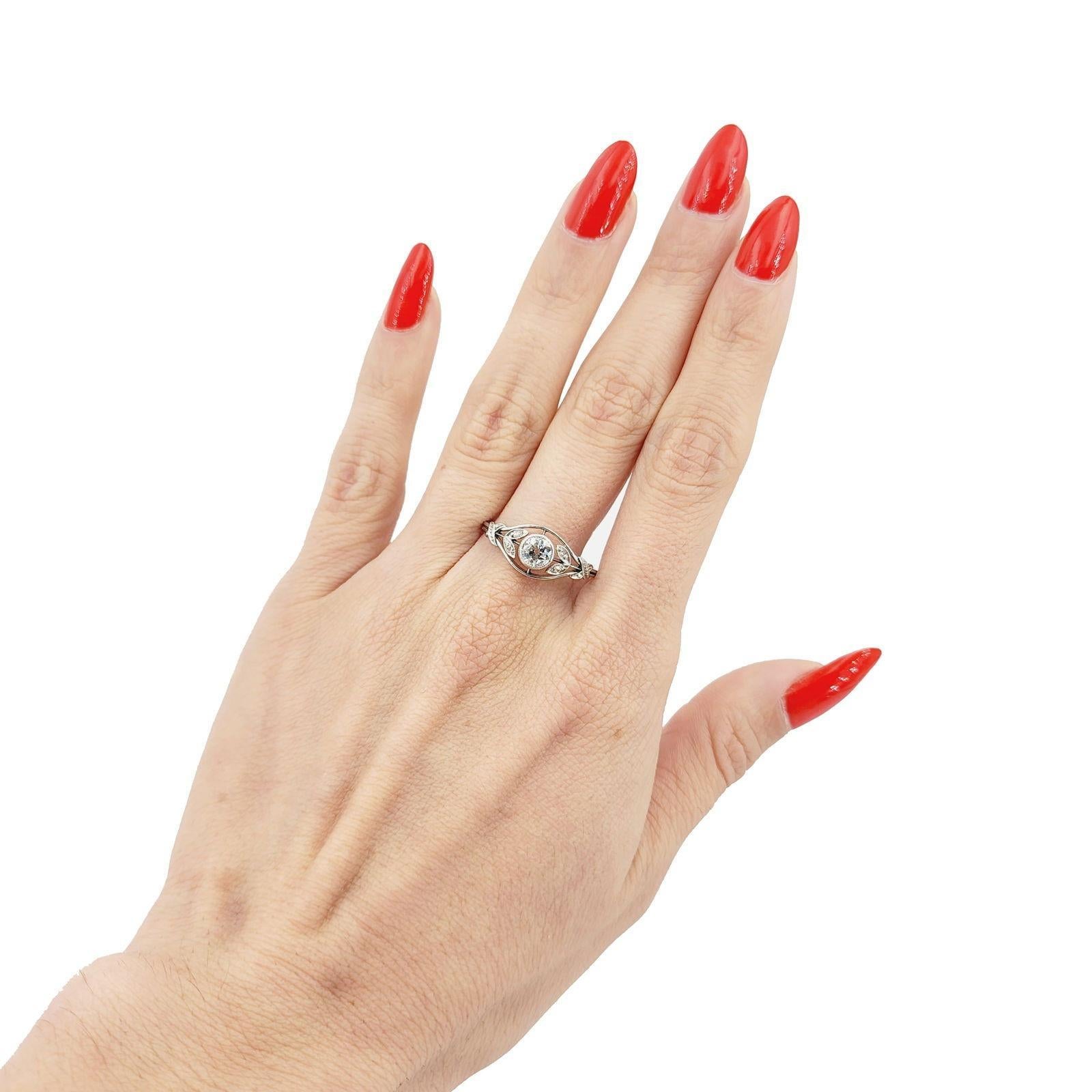 This exquisite antique ring is crafted in 18kt white gold, featuring a stunning center European cut diamond weighing approximately 0.55 carats. Graded G-H in color and SI1 in clarity, this diamond radiates a brilliant sparkle, making it a