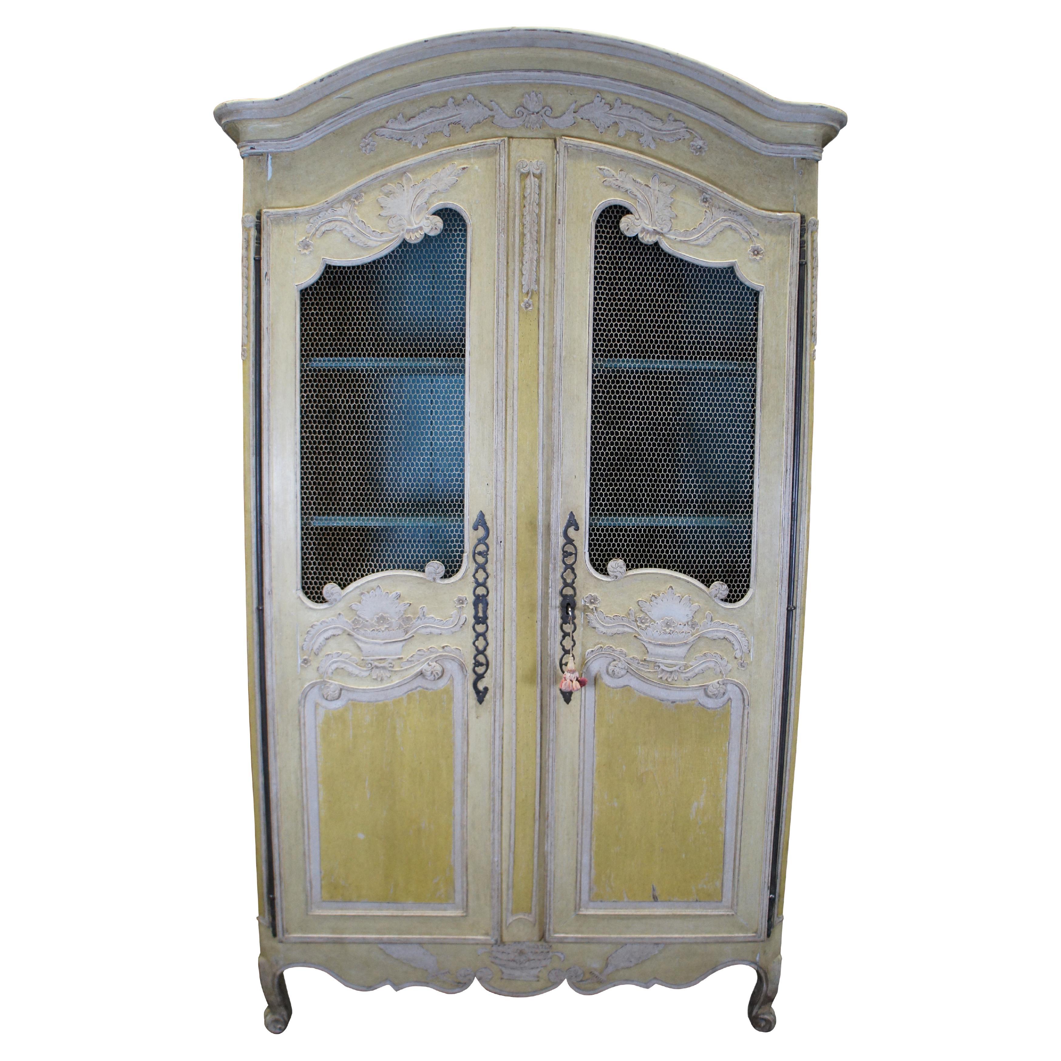 Antiguo armario francés de finales del siglo XVIII. Presenta una mezcla de estilo Country French y Provincial con acentos florales y acantos, puertas de cortina de alambre de gallinero con bisagra larga de hierro y patas cabriolé. Se abre a un