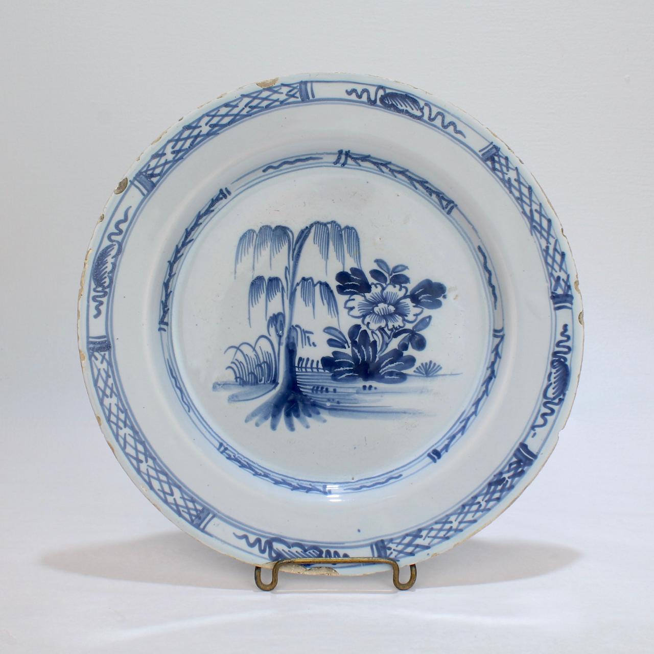 Ein schöner englischer Delft-Teller.

Stellt einen Weidenbaum und einen Lotusstrauch nebeneinander dar.

Im Stil der Chinoiserie.

Einfach ein wunderbarer Teller!

Datum:
Mitte des 18. Jahrhunderts

Gesamtzustand
Es ist in insgesamt gutem, wie