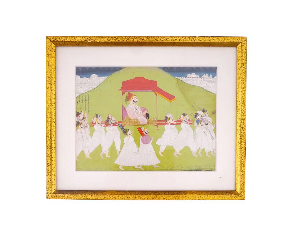 An antique late 18th century Indian miniature painting with a traditional scene of social life. In the center of the composition is an Indian Raja proudly seated in a red palanquin carried by his servants. In front and behind the palanquin are the