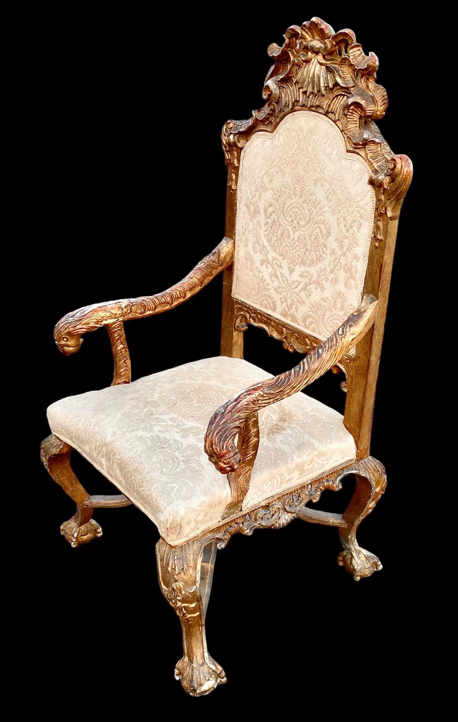 Antique Italian Rococo high back hand carved gilded wood arm chair with beige damask seat and back. 
This antique 18th century Italian Rococo armchair features c-scrolls, rocaille and foliate designs richly hand carved throughout, the deeply carved