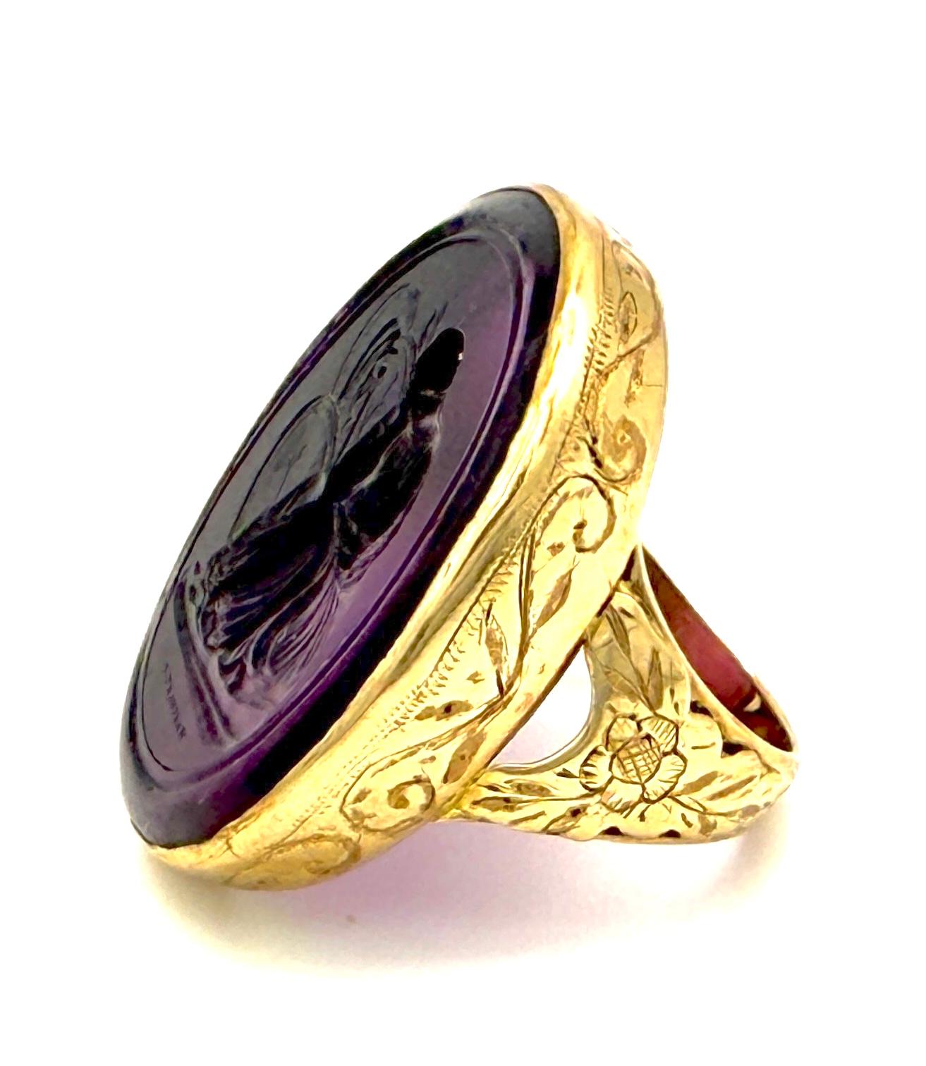 Questo anello è stato creato intorno al 1800-1810. È realizzato in oro giallo a 15 carati.  L'anello è finemente inciso con volute, foglie e fiori. Il grande calco ovale in vetro viola di un'antica calcografia è stato probabilmente realizzato da