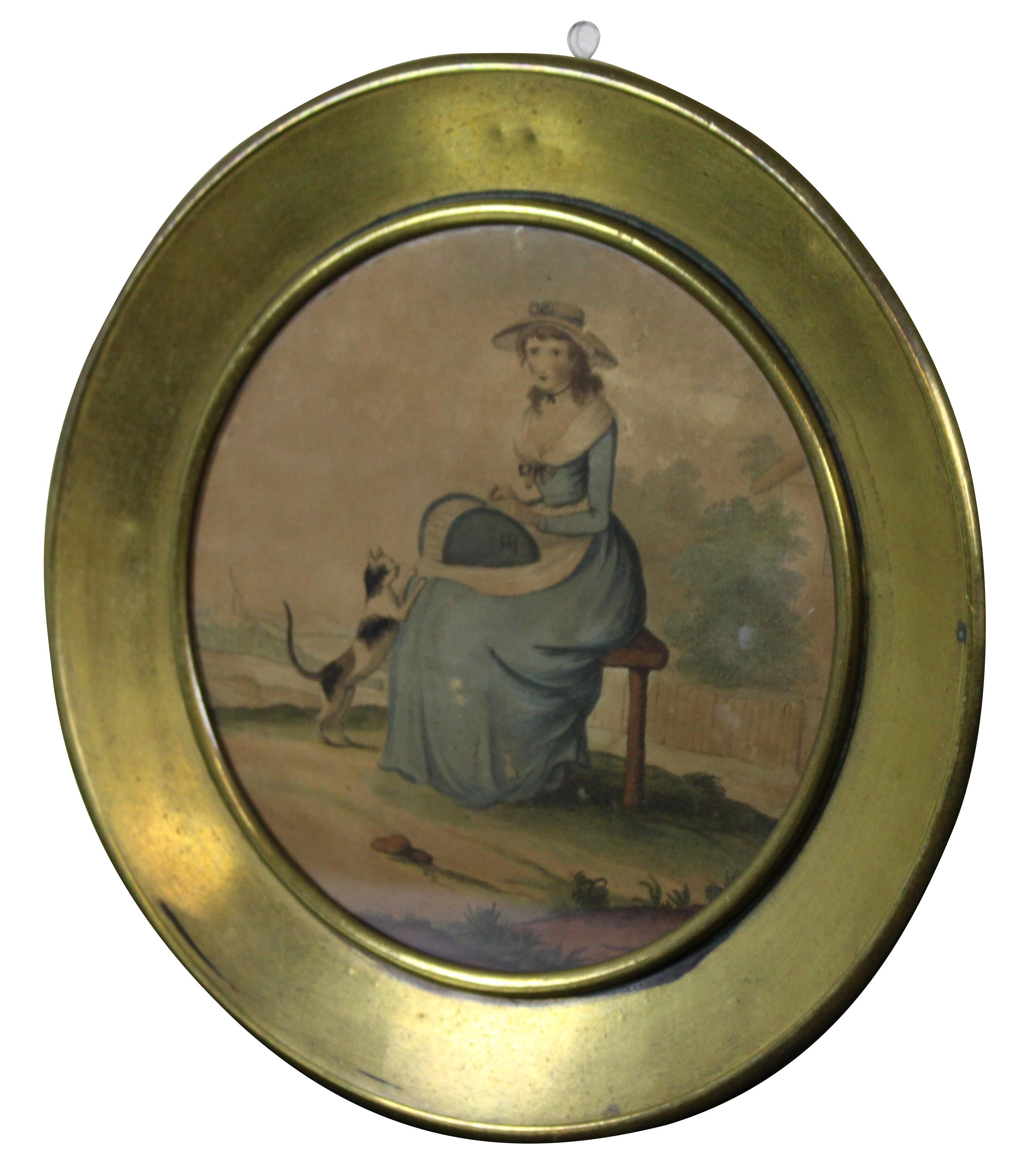 Antique colored lithograph print of an 18th century woman in a blue dress seated in a garden with a calico cat, displayed in a round brass frame.

Measures: 10.75” x 0.75” x 10.75” / Sans Frame - 7.25” x 7.25” (Width x Depth x Height).
 