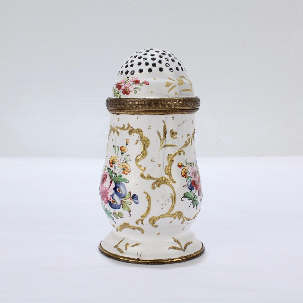 An antique 18th century Bilston or Battersea enamel muffineer or sugar shaker.

A very rare form!

With a pierced, domed top, raised gold decoration, and cartouches of floral sprays.

Measure: Height ca. 3 7/8 in.

Items purchased from this