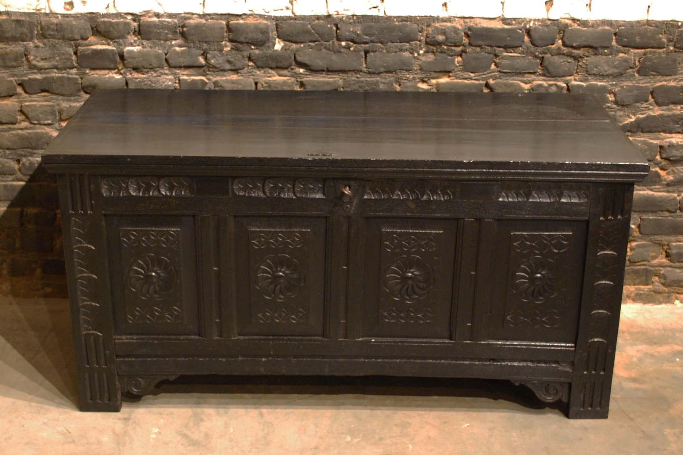 This beautiful black colored Renaissance chest or coffer was made in the early 18th century. It was made in the finest quality summer oak and stained very dark, almost black. The front of the piece has four panels with handsome carved circular