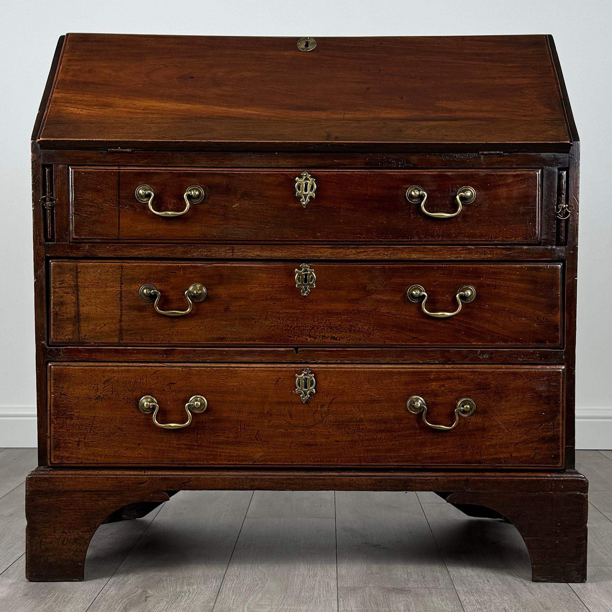 Cet exquis bureau ancien du XVIIIe siècle en acajou riche est un mélange parfait d'élégance et de fonctionnalité. 
Reposant sur de solides pieds en équerre, cette pièce comporte trois tiroirs, chacun orné de sa poignée en laiton d'origine, ajoutant
