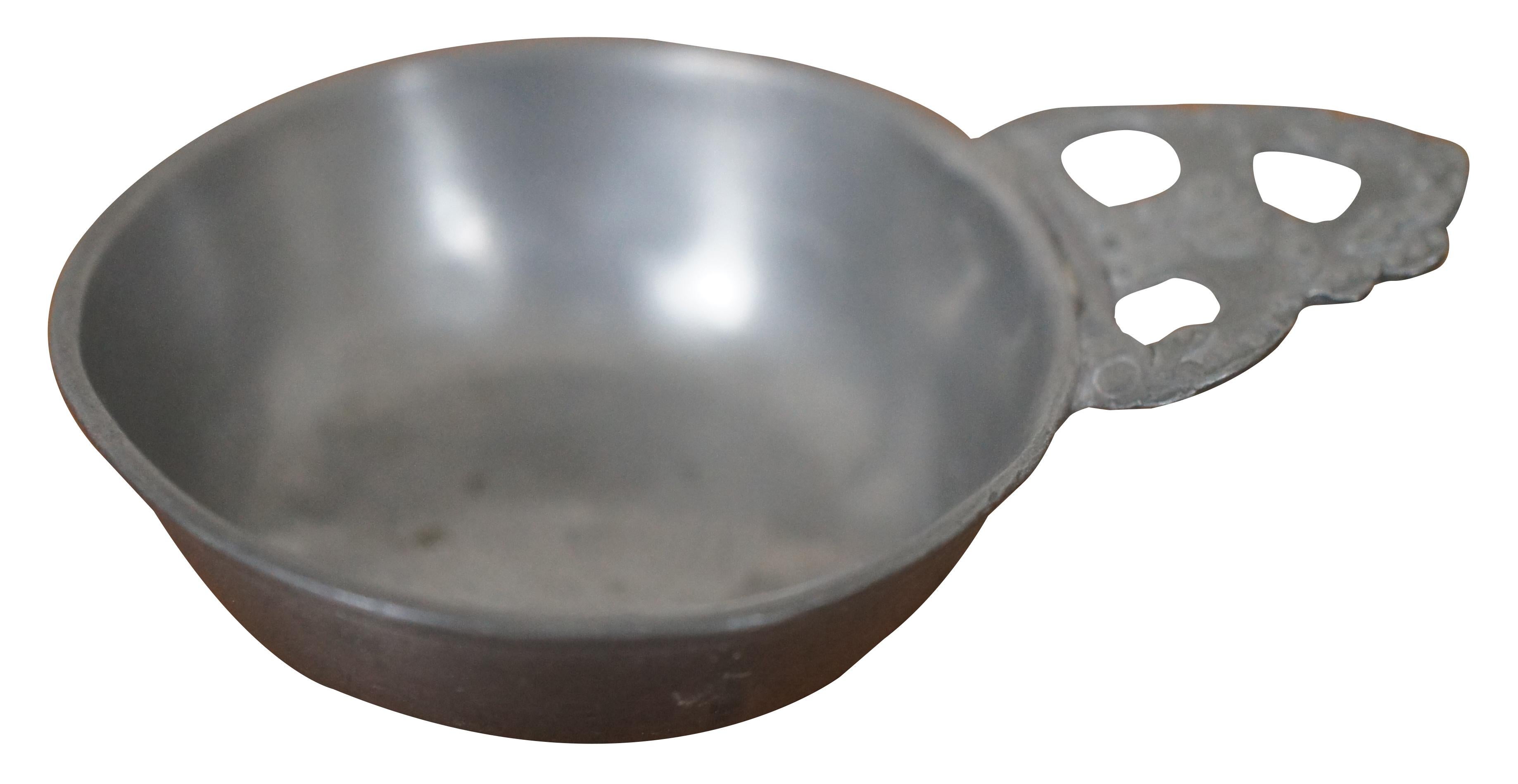 Antique circa 18th century childs pewter porringer / tastevin featuring straight sides with rim flange, flat base, triangular bracket with wedge under the ear, and primitive lobed ear. 

Porringers were small food bowls used for porridge or wine