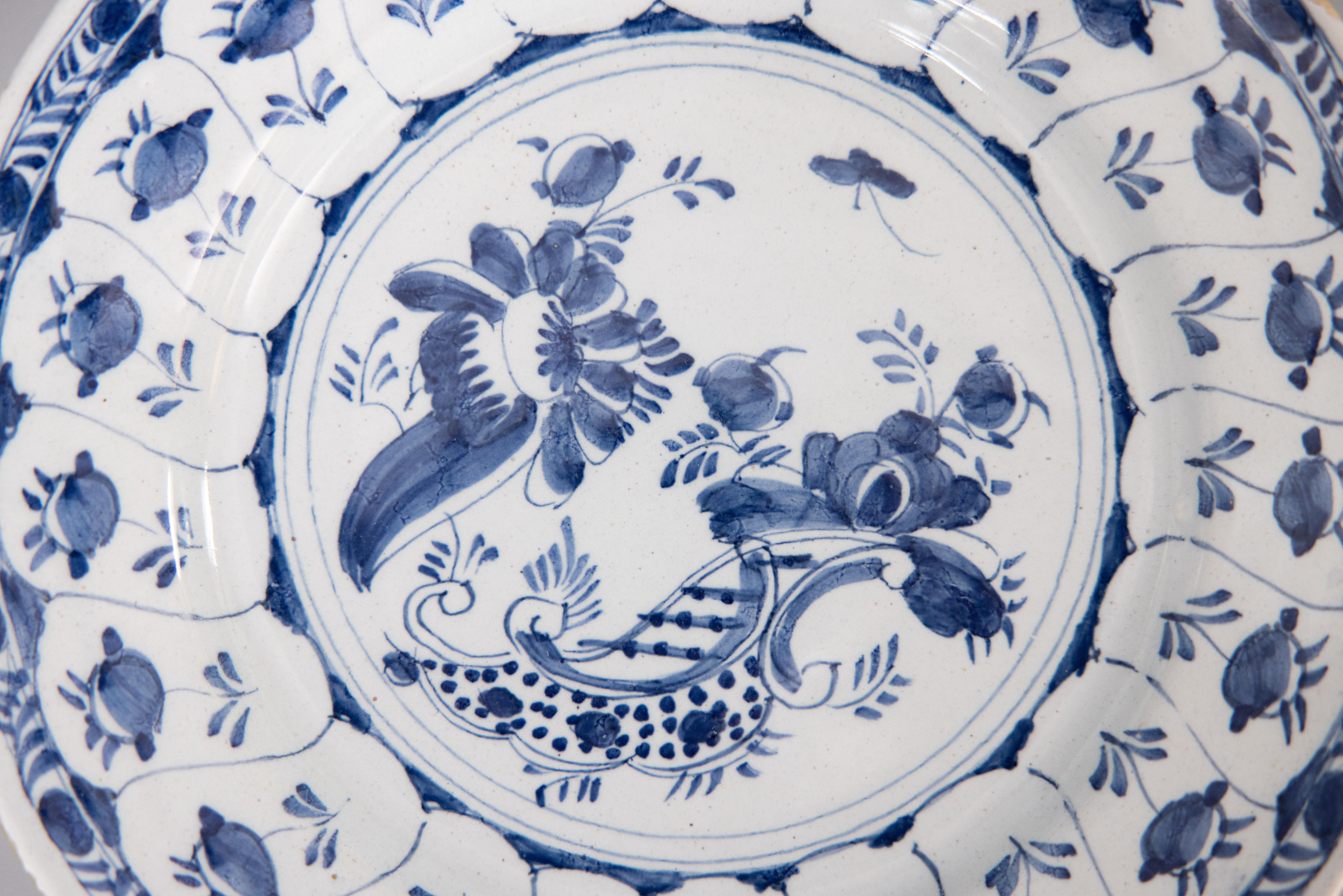 Superbe assiette florale en faïence hollandaise de Delft du 18e siècle. Cette jolie assiette est ornée de fleurs, d'un papillon et d'une bordure feuillue peints à la main en bleu cobalt et blanc. Elle serait merveilleusement ajoutée à une