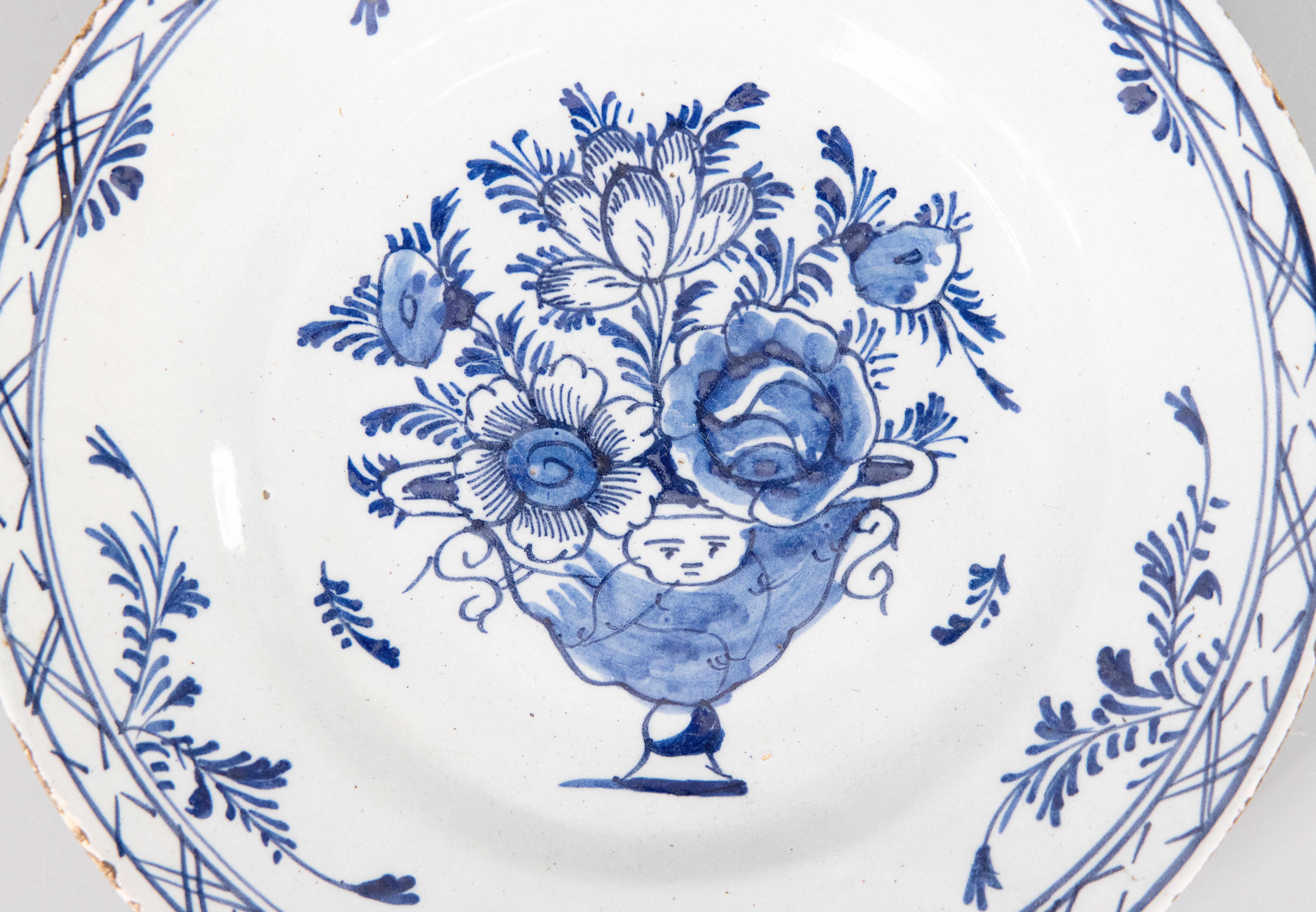 A lovely antique 18th-Century Dutch Delft faience plate with a hand painted floral arrangement in a cherub vase in classic blue and white. It would look fabulous displayed on a wall or shelf in any room.

Dimensions
9ʺW × 1.25ʺD × 9ʺH