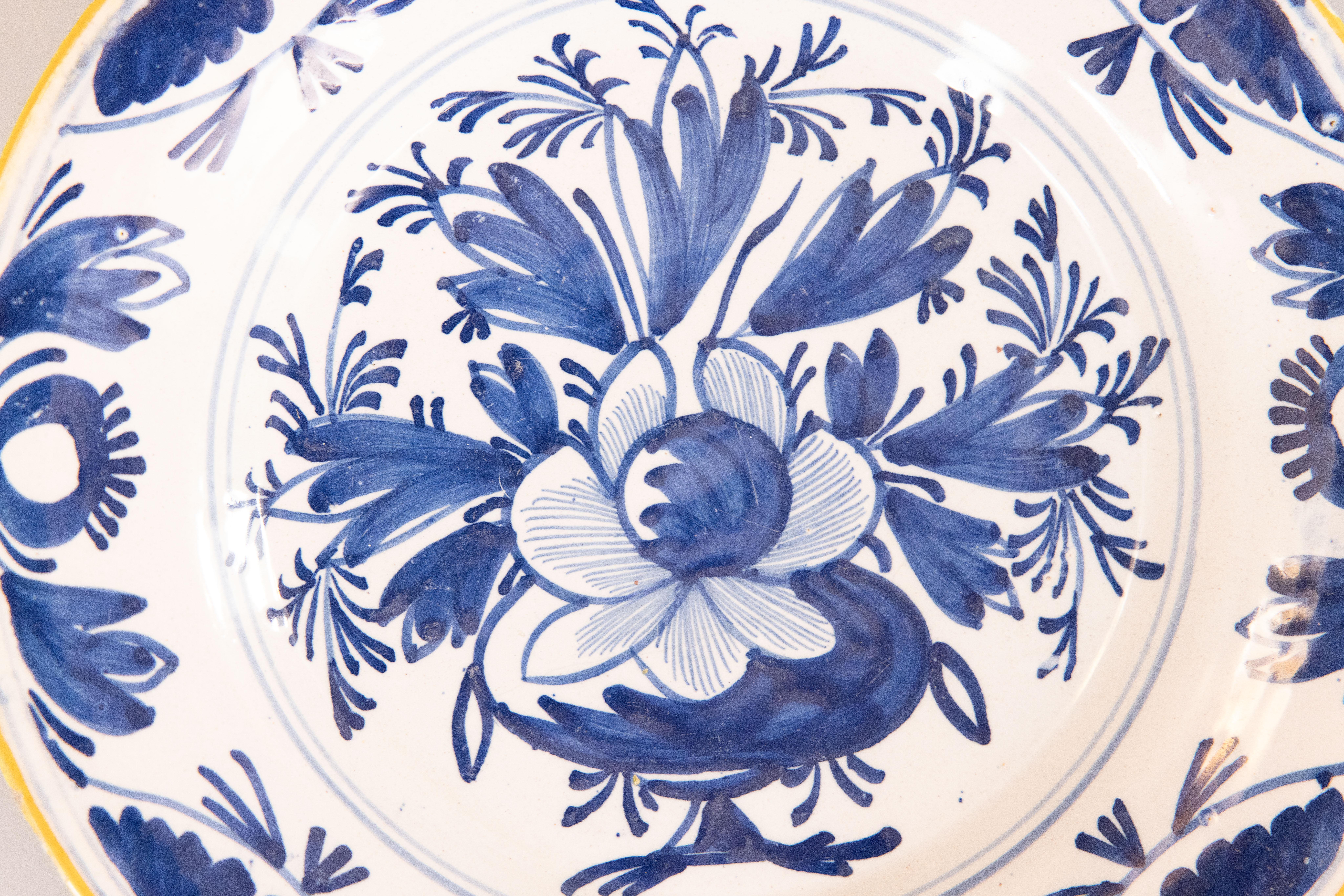 Precioso plato floral de loza holandesa de Delft del siglo XVIII. Este precioso plato tiene un centro en forma de maceta pintado a mano con un borde foliado decorativo en vibrante azul cobalto y blanco con un borde amarillo dorado. Quedaría fabulosa