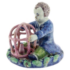 Figurilla antigua de Delft holandés del siglo XVIII de un niño que sostiene una jaula con pájaro