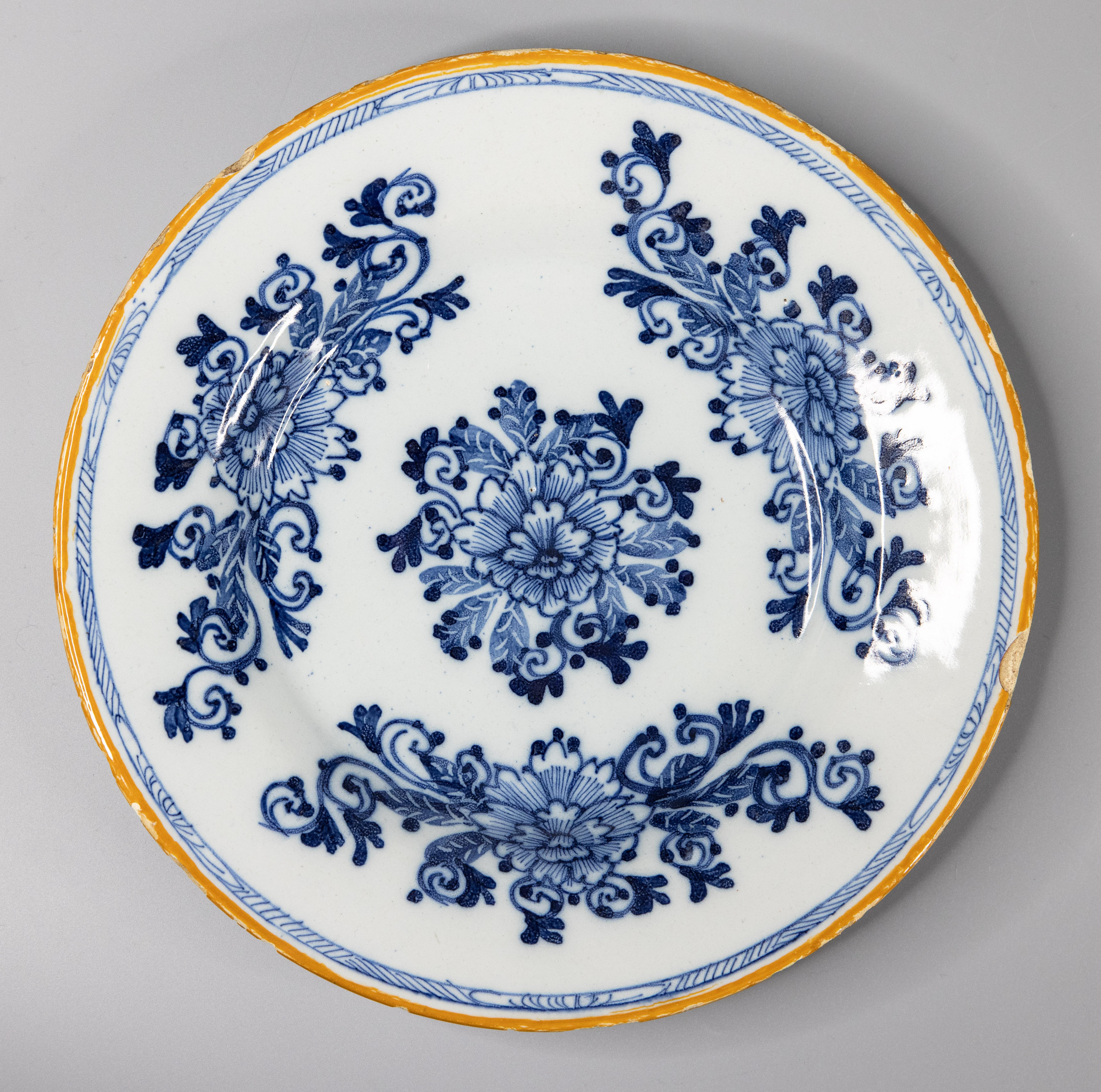 A lovely pair of antique 18th-Century Dutch Delft hand painted floral plates in vibrant cobalt blue and white with a yellow gold rim, circa 1760. Maker's mark 