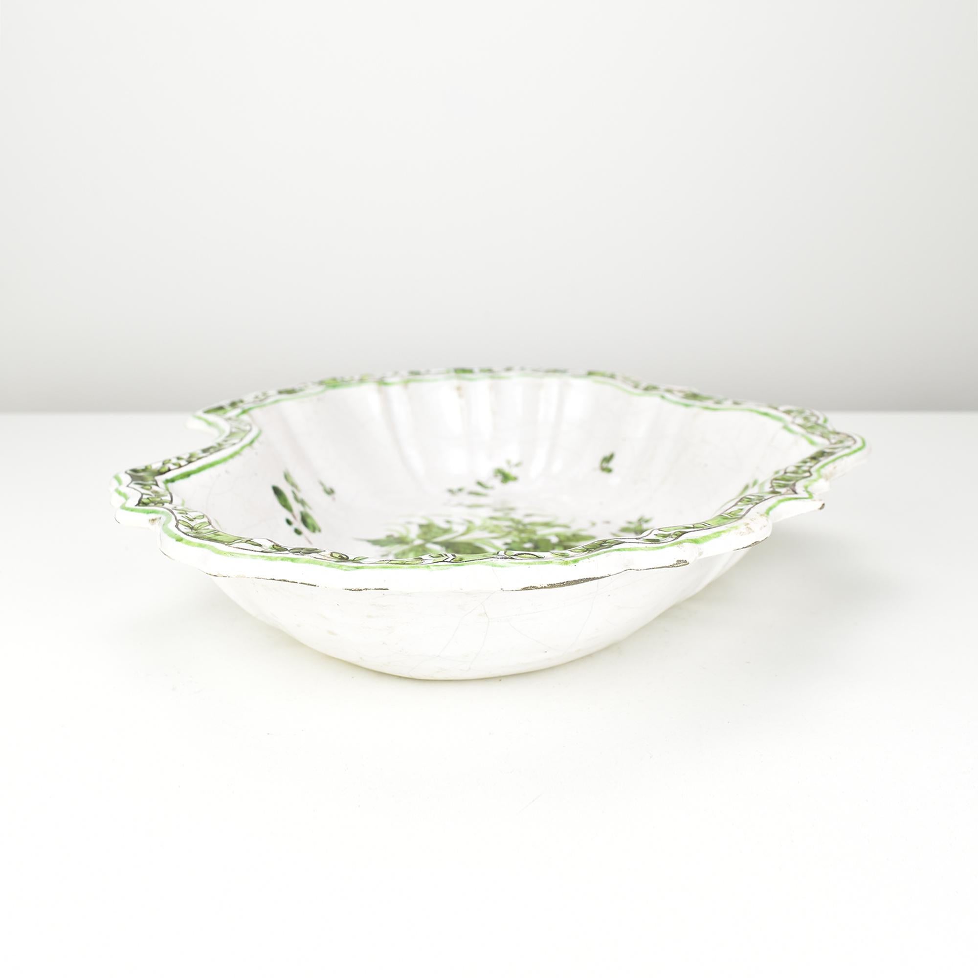 Diese exquisite Barbierschale aus holländischem Delft oder Samadet aus dem 18. Jahrhundert hat eine klassische, gelappte Form mit einem gekerbten Rand, der traditionell für die Rasur verwendet wurde. Das Stück ist in lebhaftem Grün handbemalt und